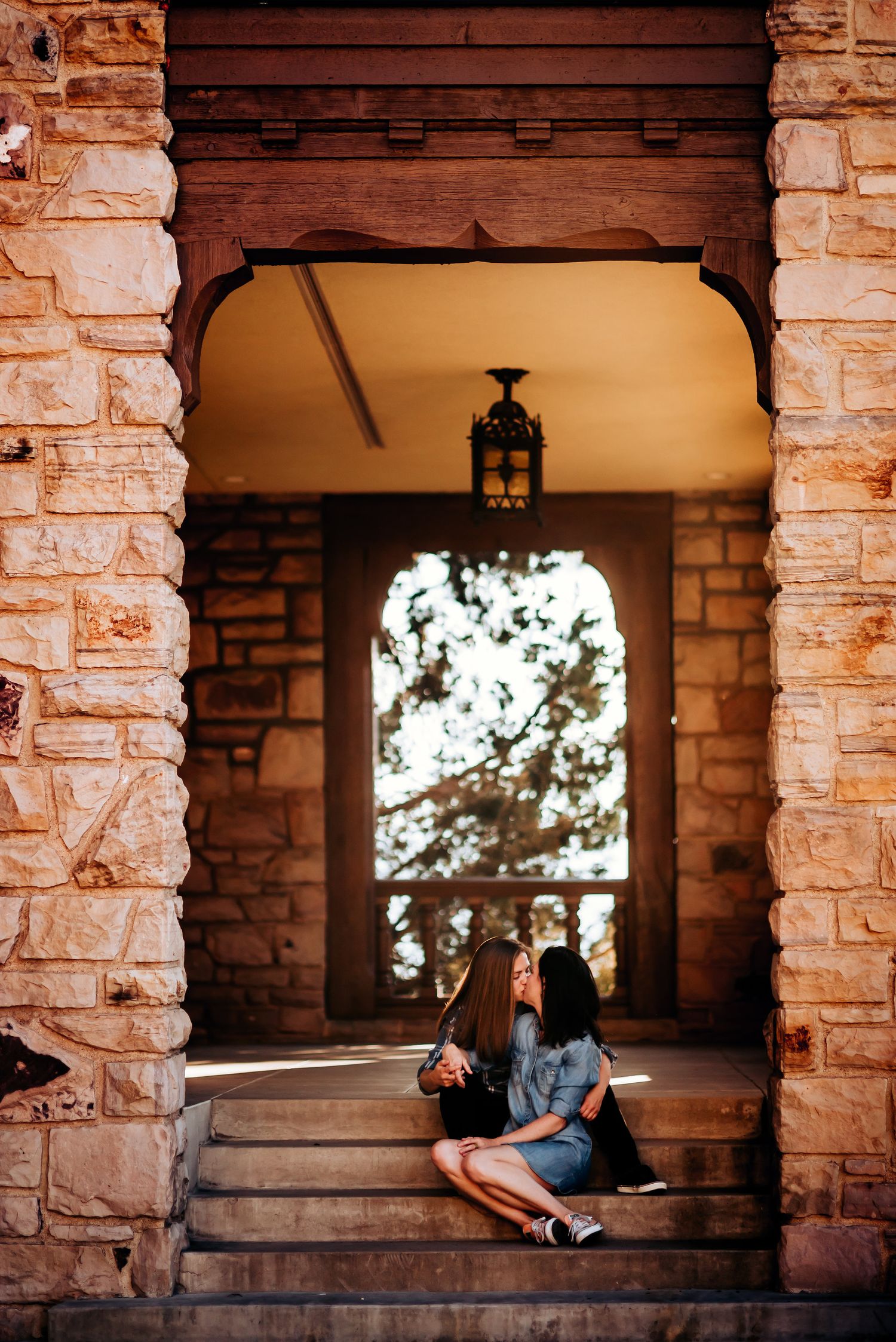 A figure sits in a stone archway at sunset with a hanging lantern overhead creating a warm atmospheric scene.