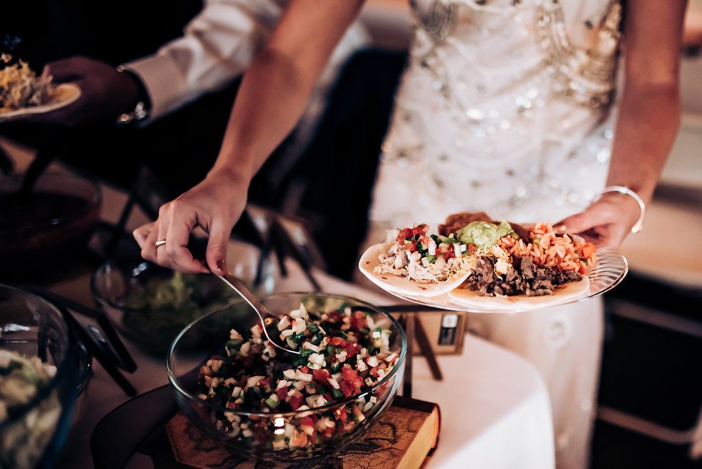 Hands serving food from elegant buffet display with various salads and dishes.