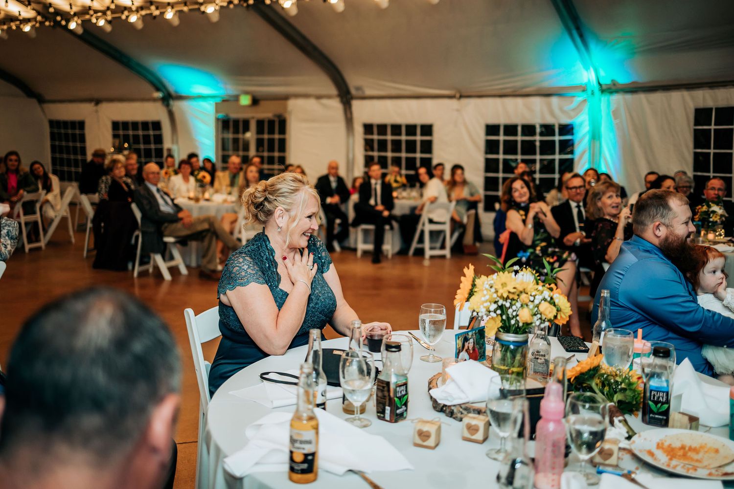 Evening wedding reception with guests seated at tables under blue ambient lighting.