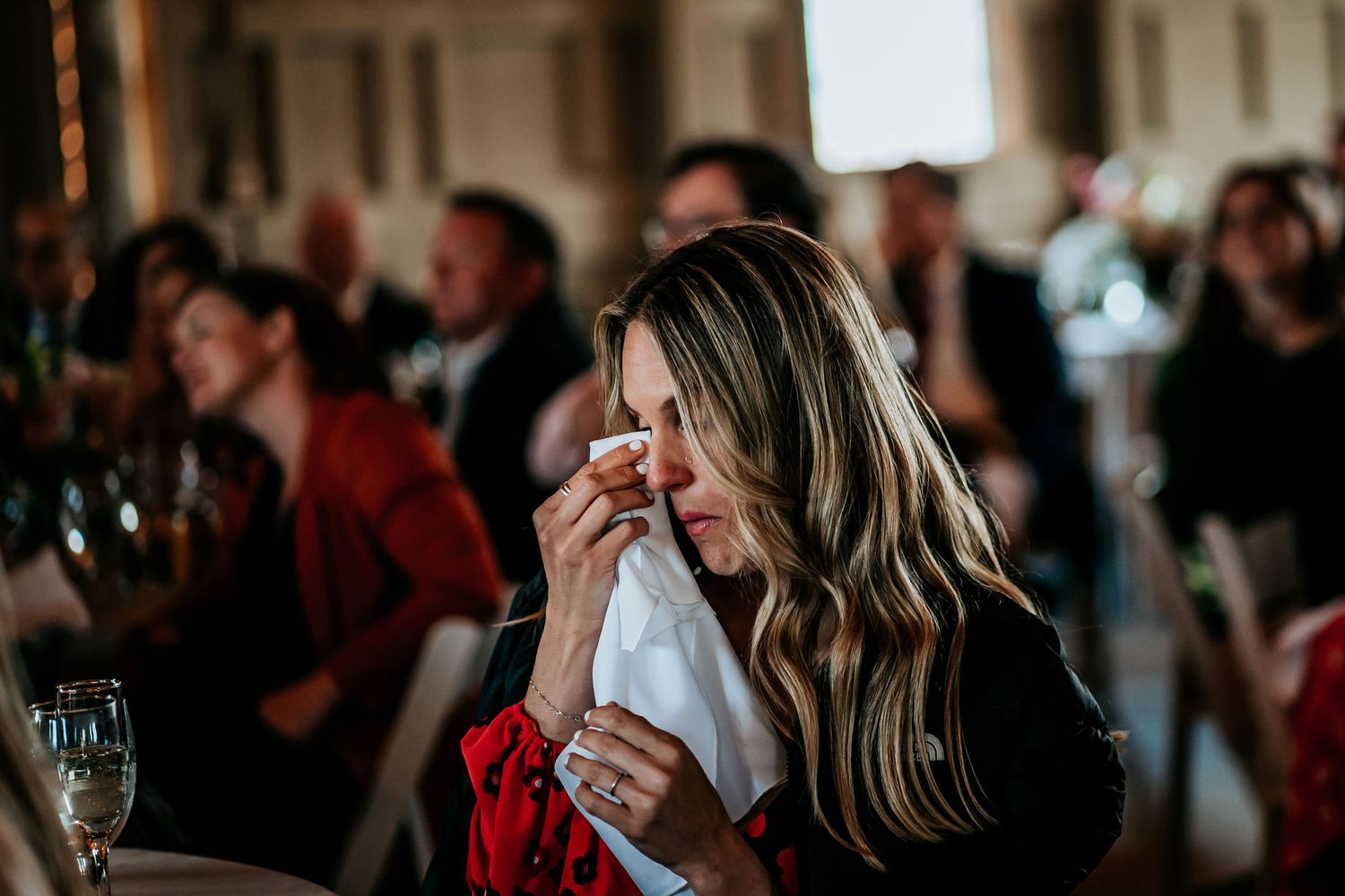 An emotional guest dabs tears with a napkin during a moving dinner reception speech.