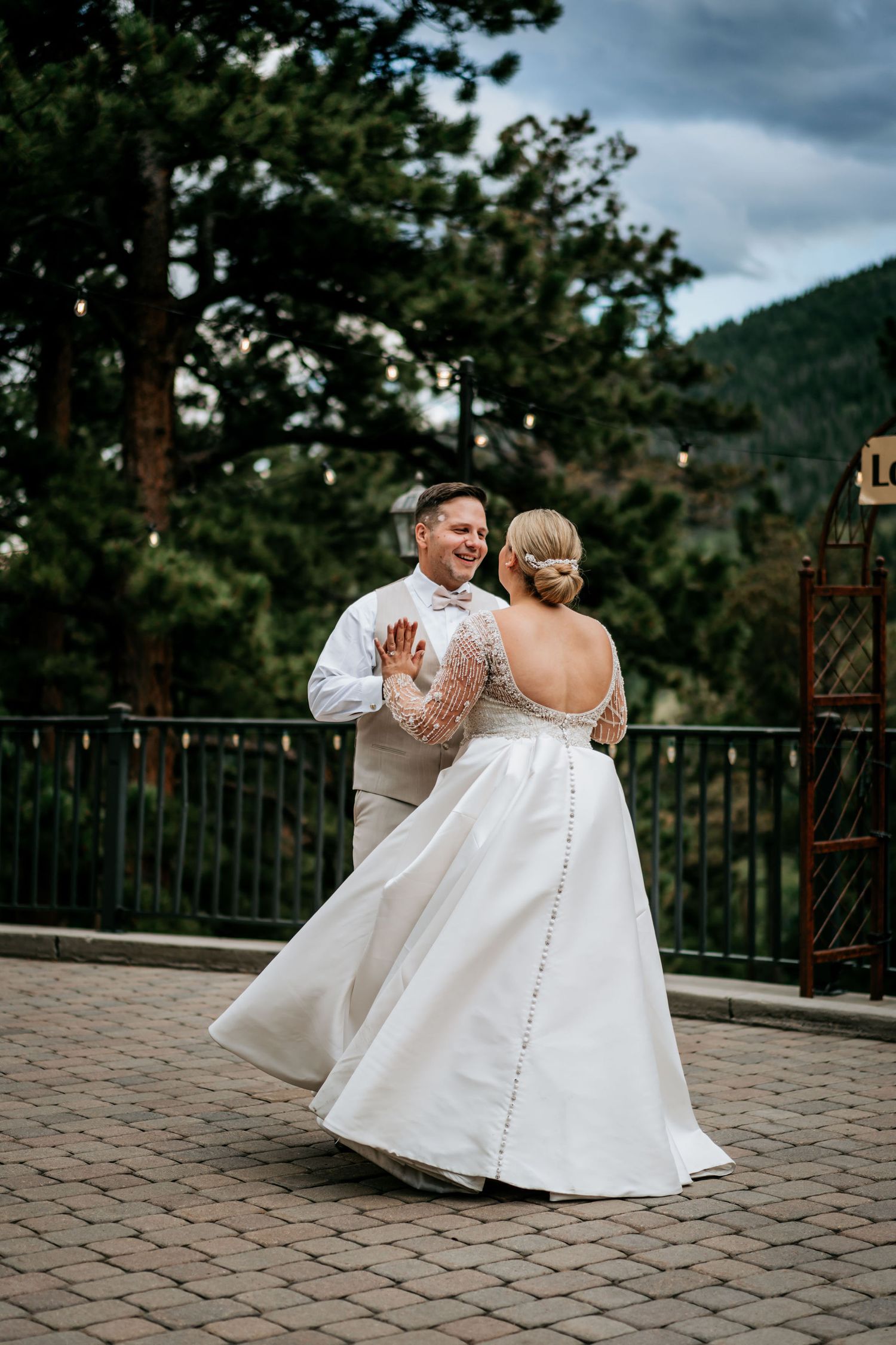 Couple dancing on a stone patio with mountain scenery in the background.
