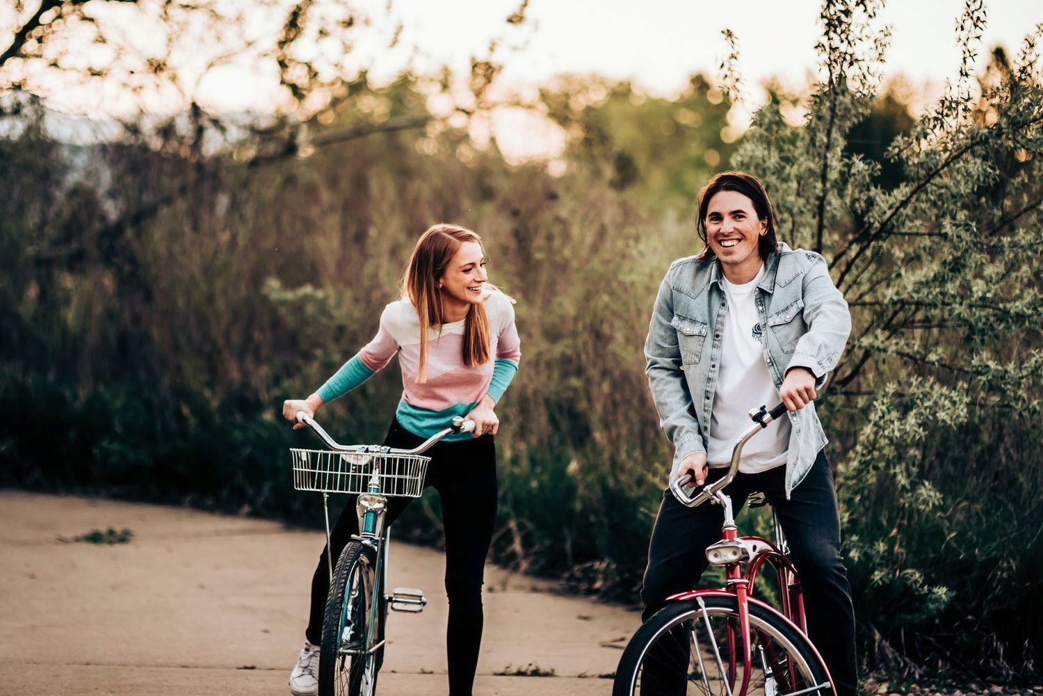 Couple sharing joyful moments while riding bicycles in golden afternoon light.