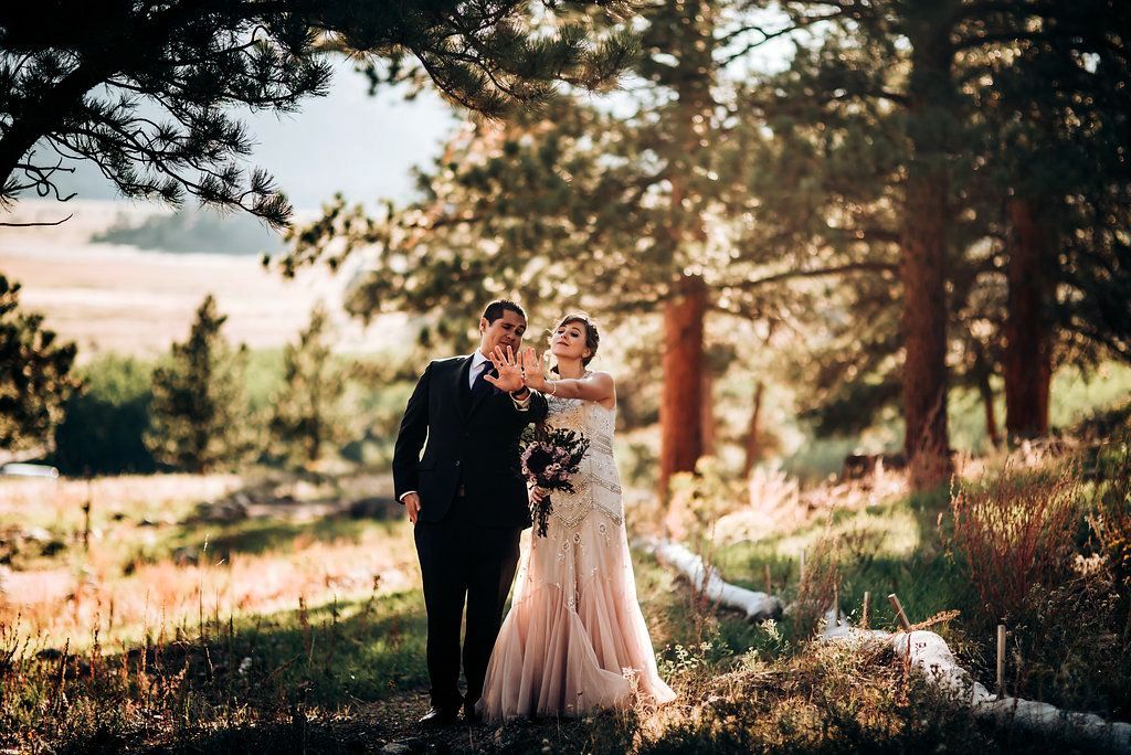 A wedding couple poses against a scenic mountain backdrop during golden hour.