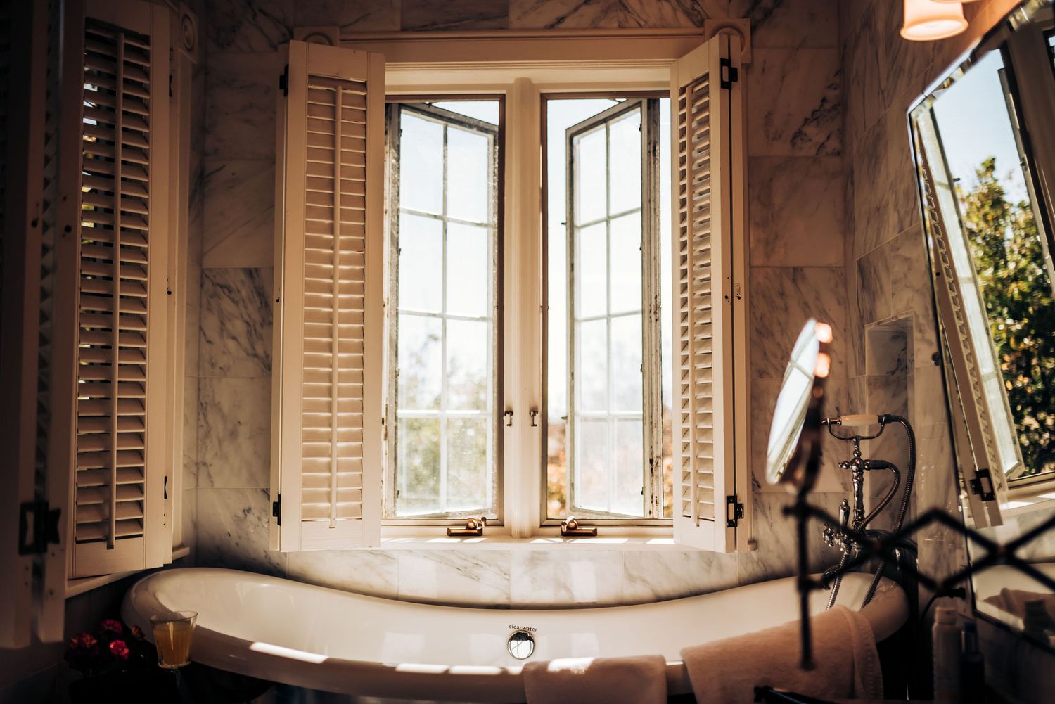 Elegant bathroom with marble walls features a corner window and garden tub.