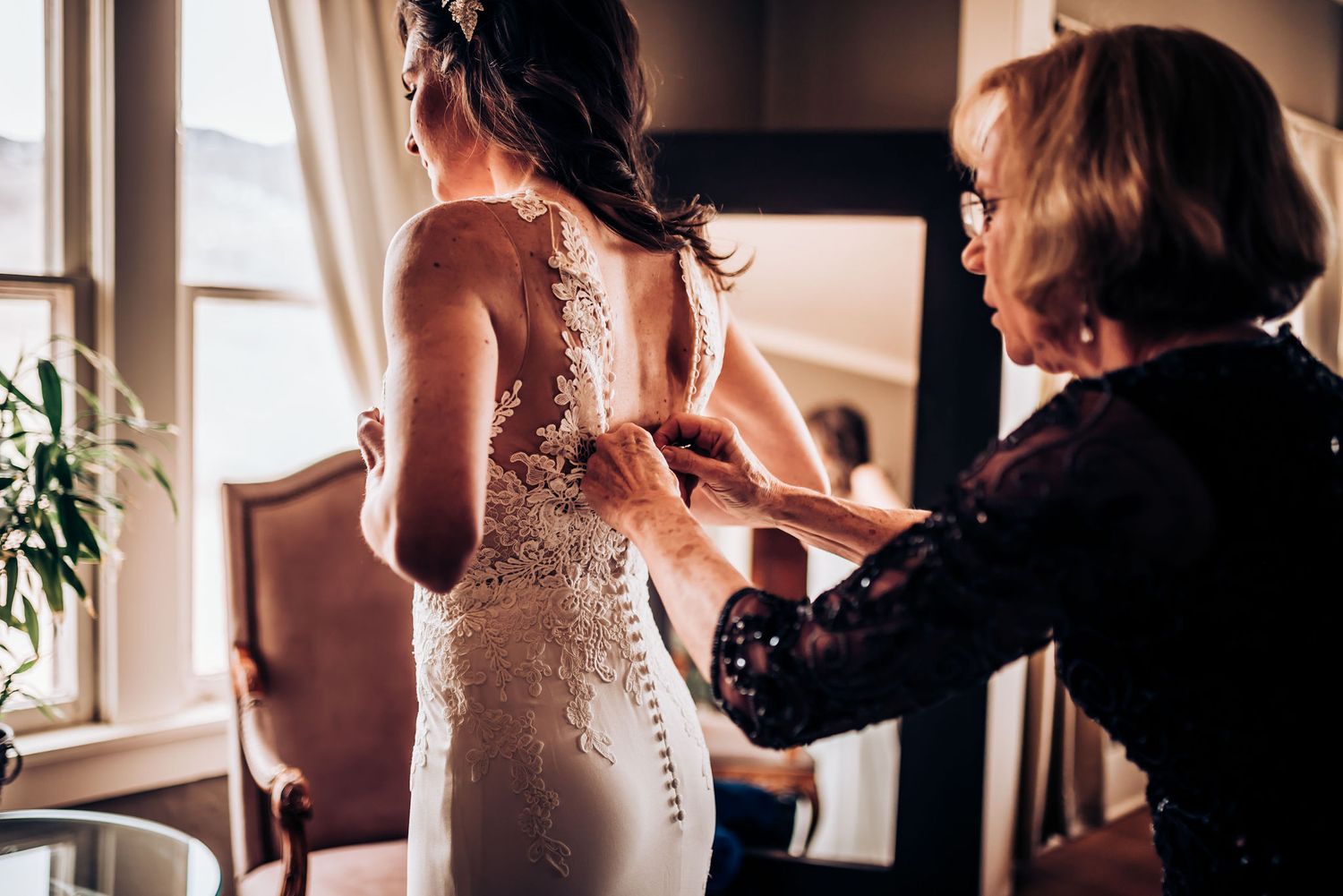Wedding dress preparation with intricate lace detail being adjusted in natural light.