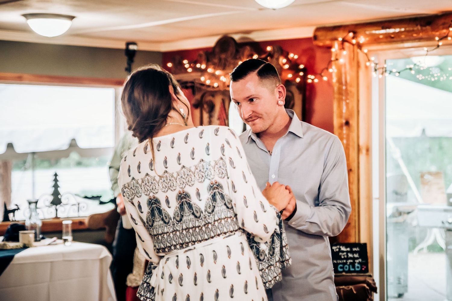 Dancing couple in an intimate moment at a reception hall with decorative lighting.