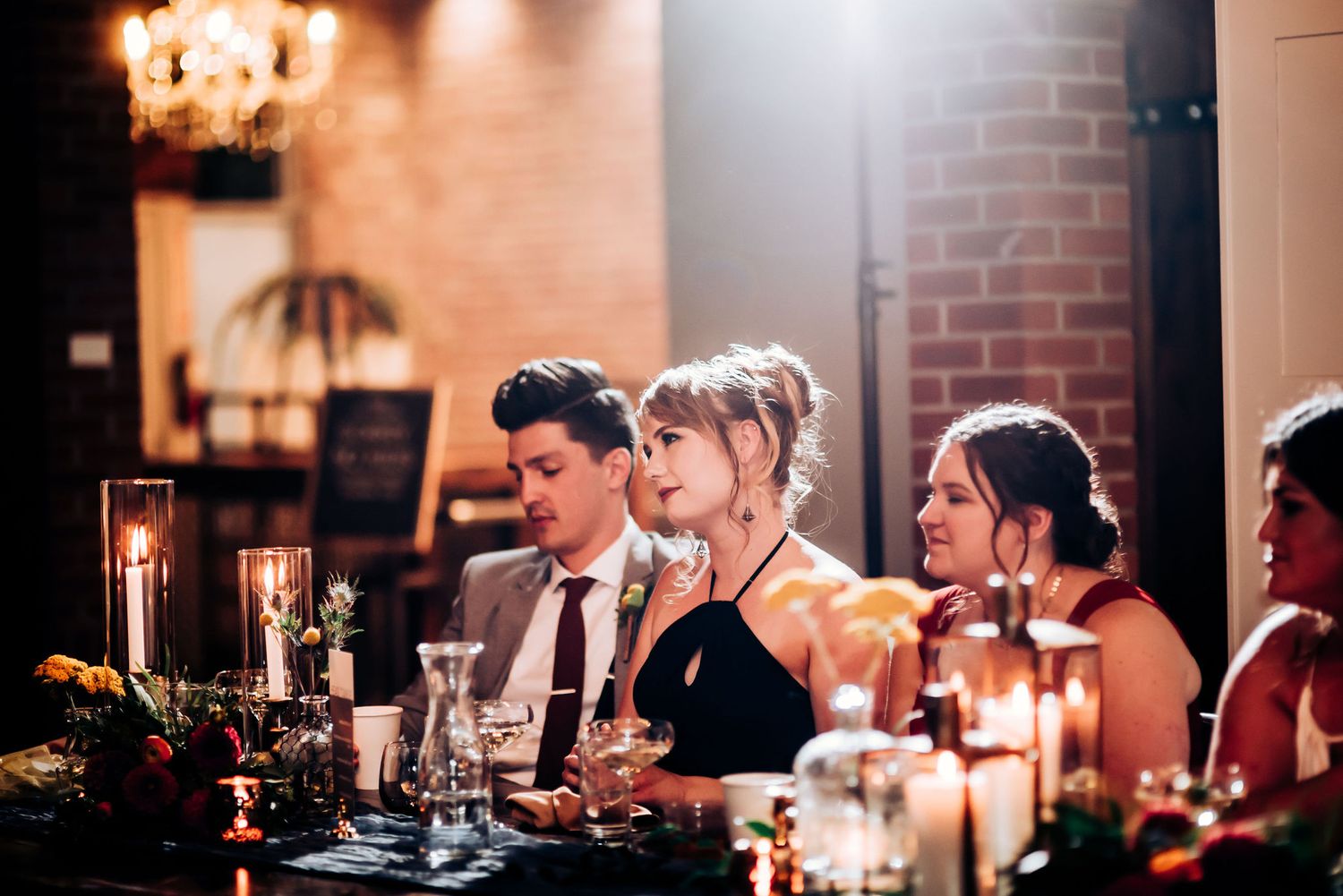 Guests seated at a long table with candles and floral decorations during an evening celebration.