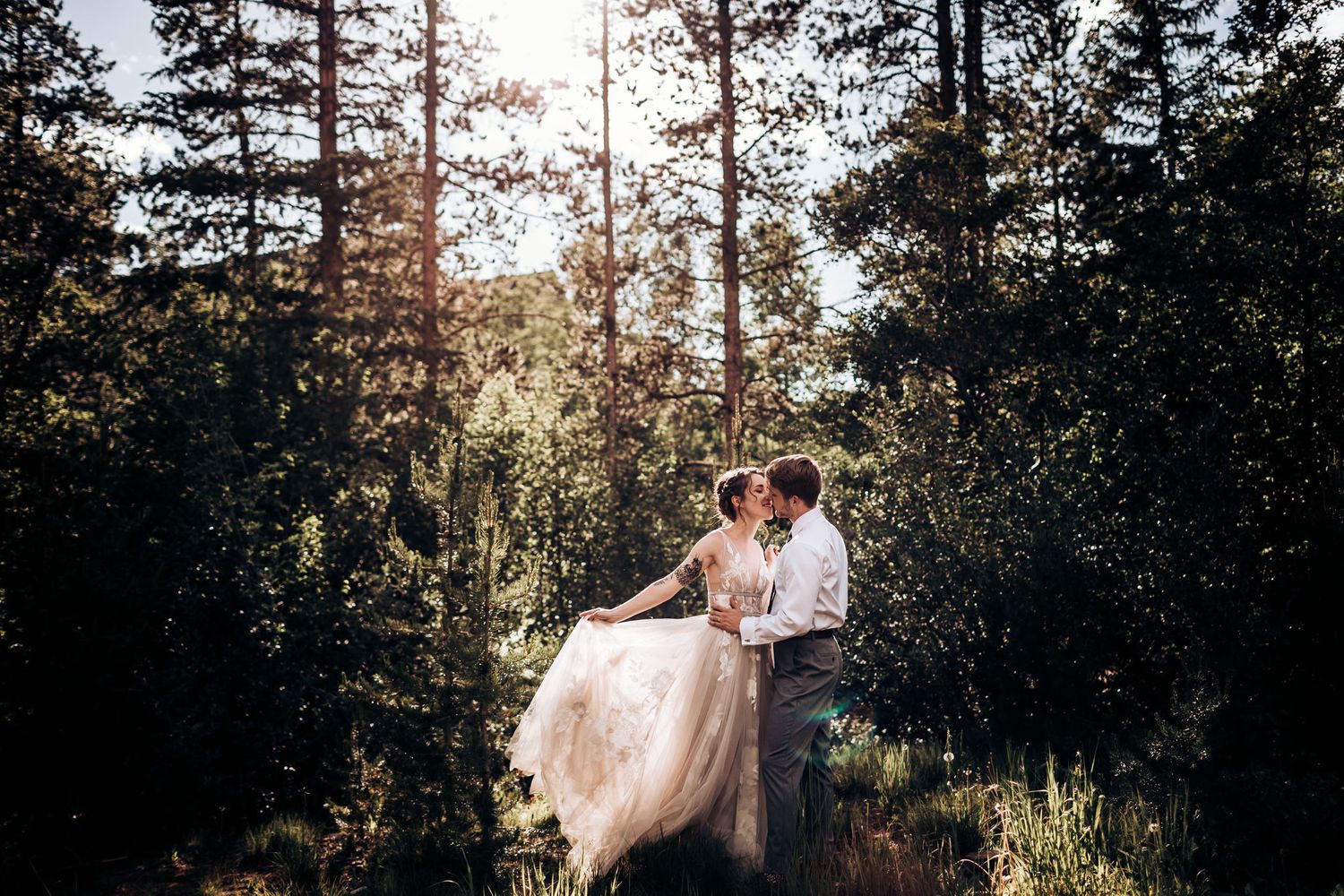 A magical sunset wedding photo in a forest clearing with the dress catching golden light.