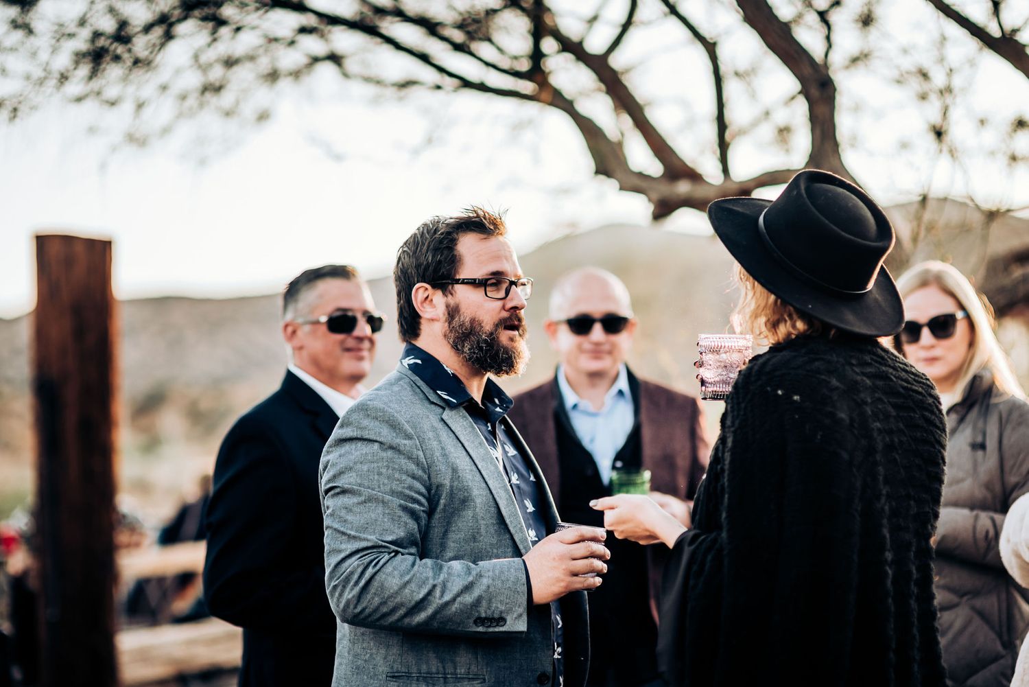 Guests mingling at an outdoor desert event with mountains in the background.