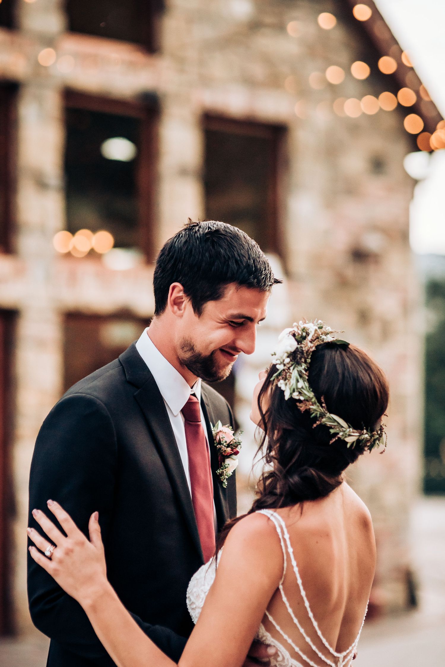 A romantic wedding photo capturing an intimate moment between newlyweds with warm string lights in the background.