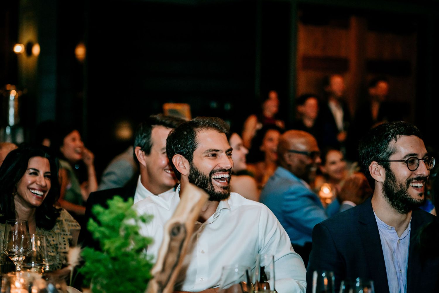 Guests enjoy a lively moment during an evening dinner event with ambient lighting.
