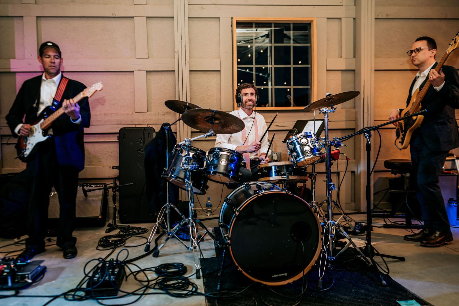 Live band performs at an event with bass, drums and instruments set up on stage.