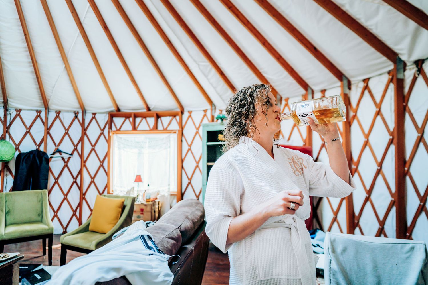 A celebratory moment captured in a cozy yurt as someone drinks from a glass in a white outfit.