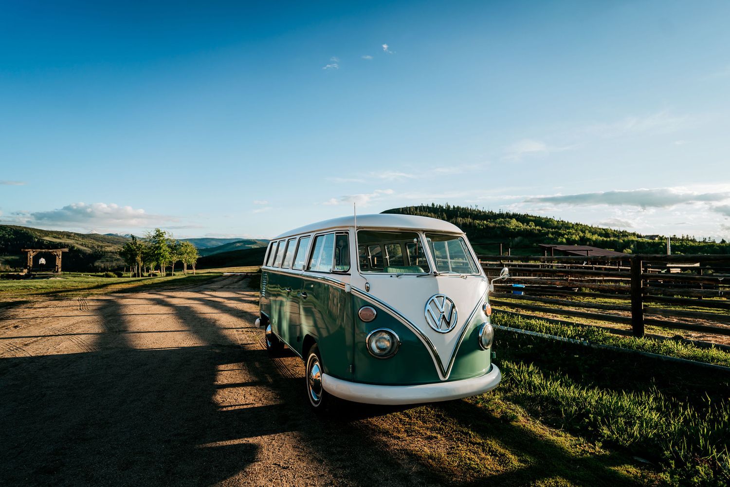 Retro VW van on dirt road with mountain landscape in background.