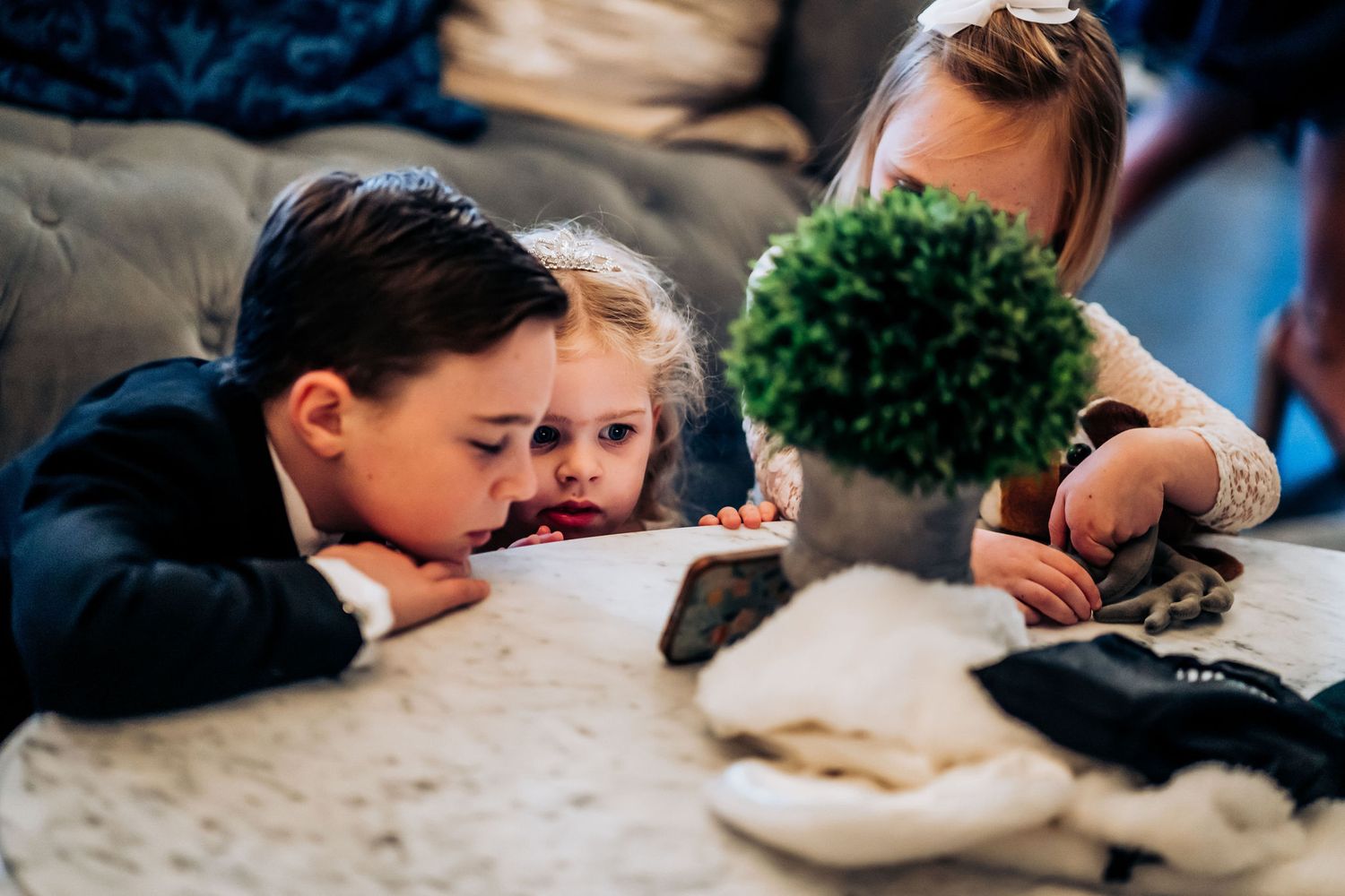 Children lean over a table together while engaged in an activity.