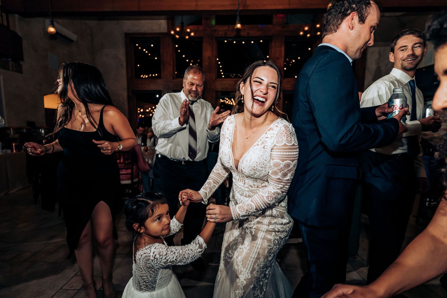 Joyful dancing at wedding reception with guests celebrating on wooden dance floor.