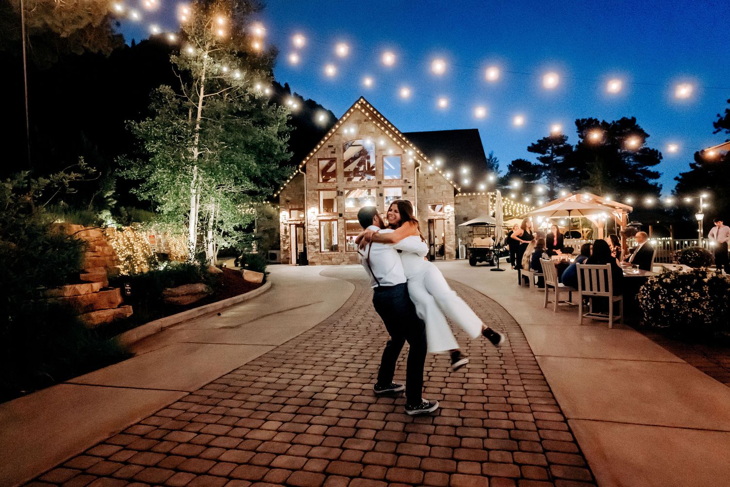 A romantic dance dip on a brick pathway with a beautifully lit barn in the background.
