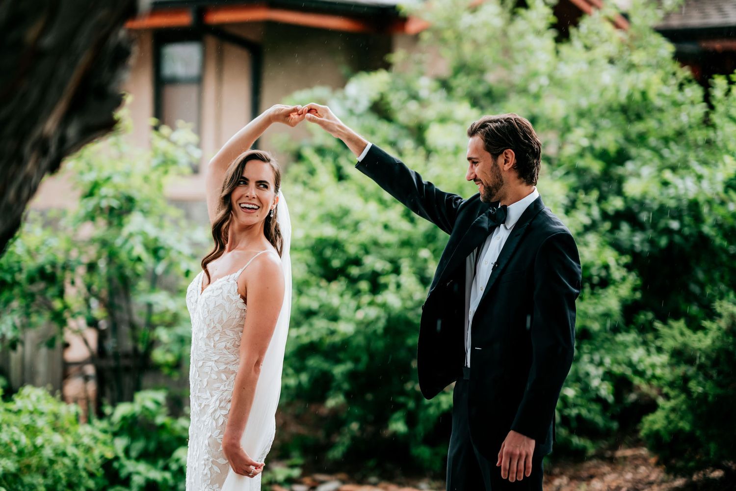 A couple shares a romantic dance moment in a garden setting with natural lighting.