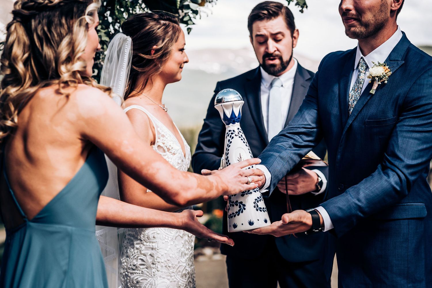 Wedding party pouring champagne together during outdoor mountain ceremony.