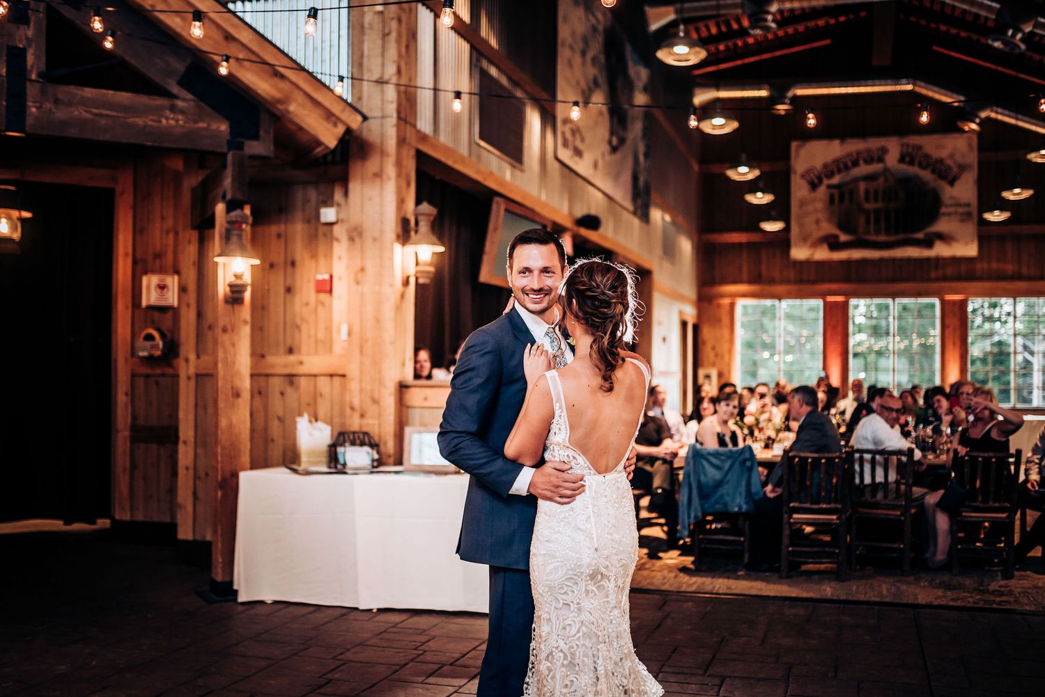 A romantic first dance in an elegant rustic venue with wooden beams and warm lighting.