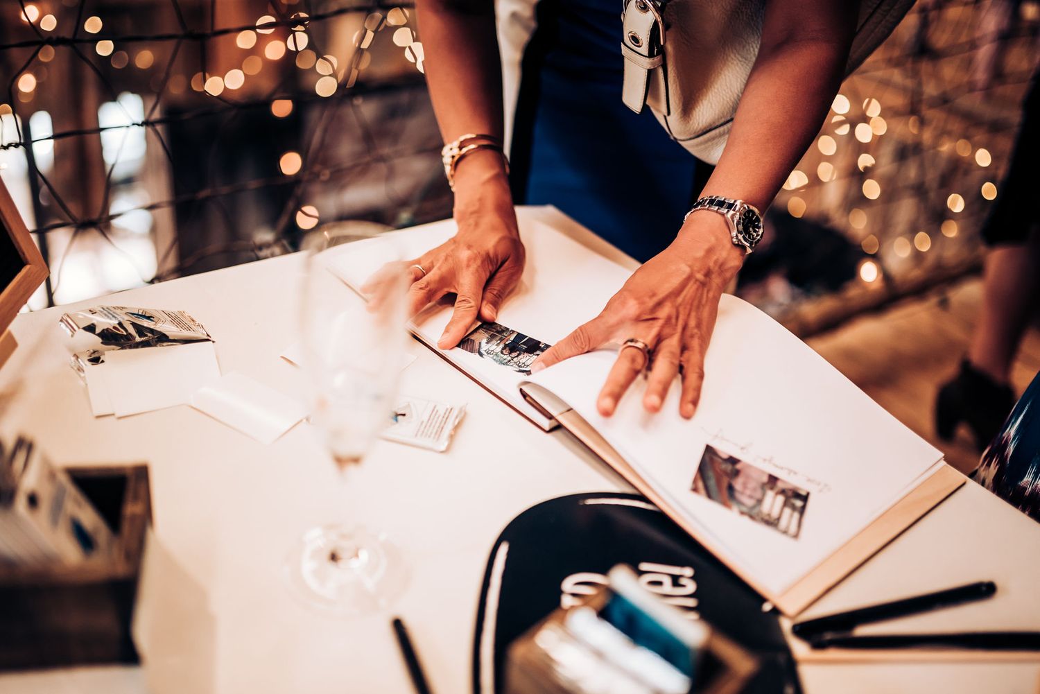 Hands writing or signing something on paper at a decorated table.