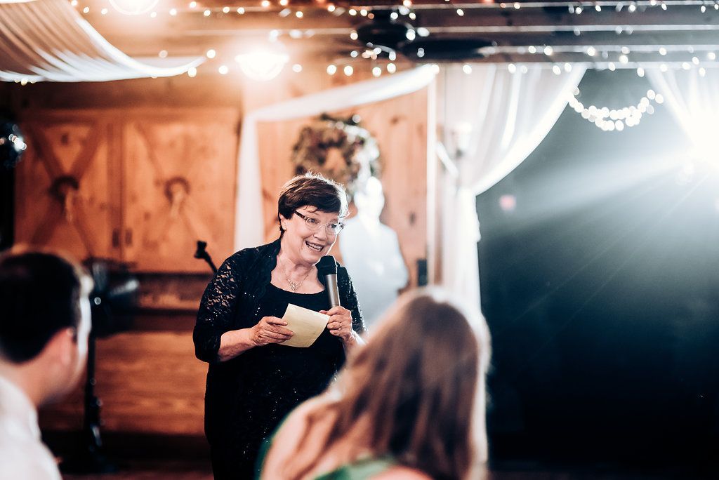 Speaker delivers a speech at an intimate wedding reception decorated with twinkling fairy lights.