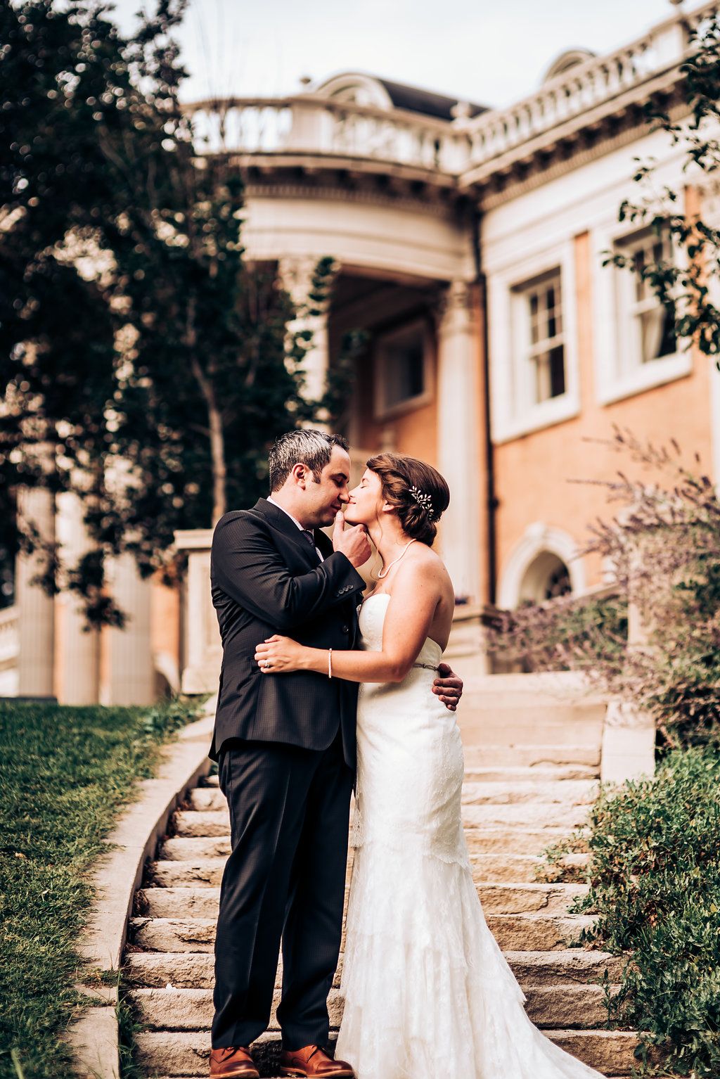 Wedding couple embraces on stone steps of a historic building with beautiful architecture.