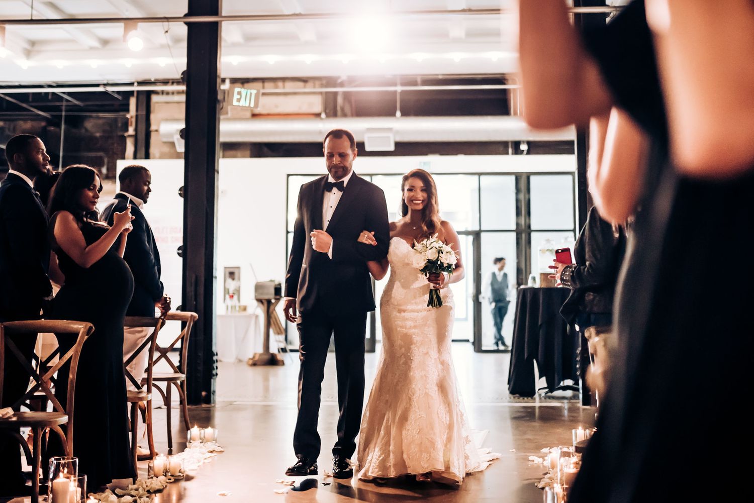 A couple makes their grand entrance into their wedding reception through a candle-lit aisle.