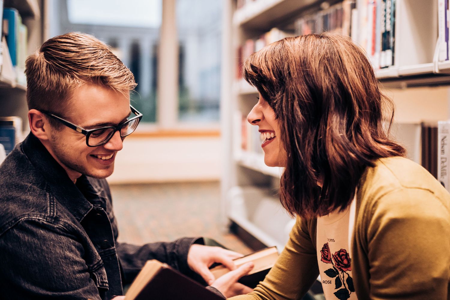 A couple shares a laugh while studying in a library.