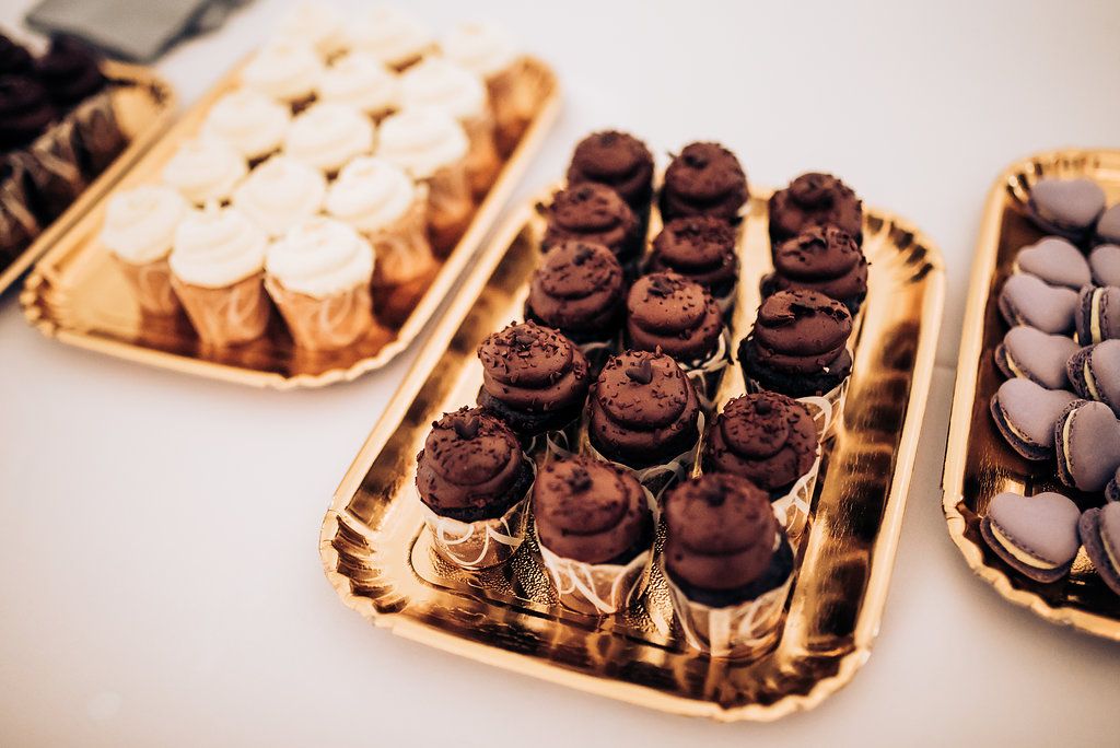 Elegant gold trays filled with chocolate and vanilla desserts at a wedding reception.