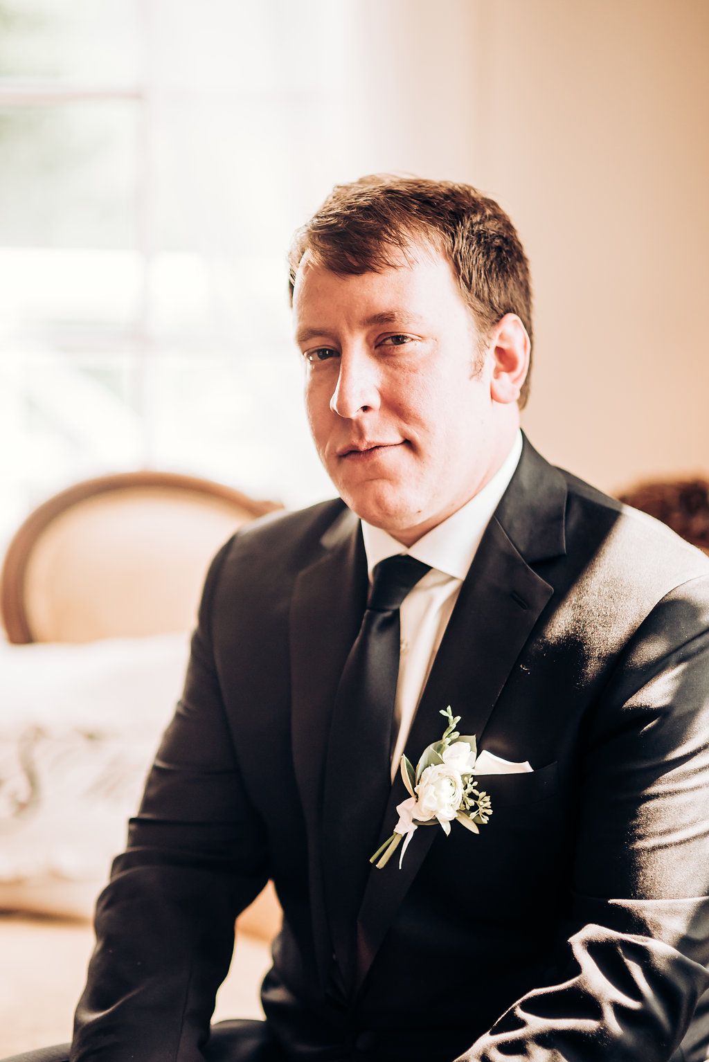 Groom in classic black suit and tie with boutonniere.