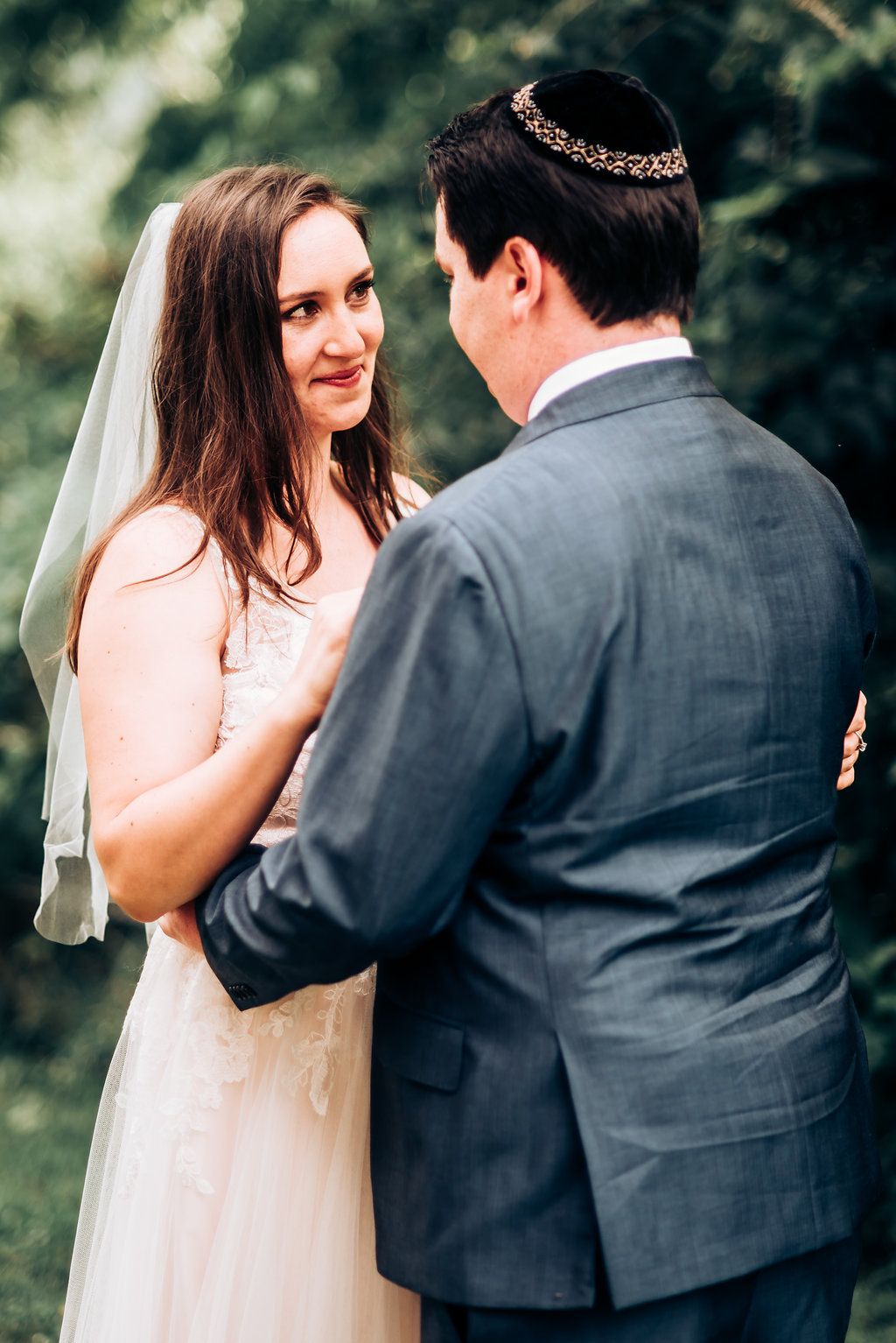 Tender moment between couple during Jewish wedding ceremony outdoors.