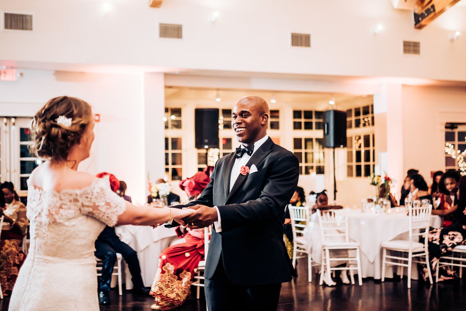 Couple shares their first dance on elegant hardwood floor during wedding reception.