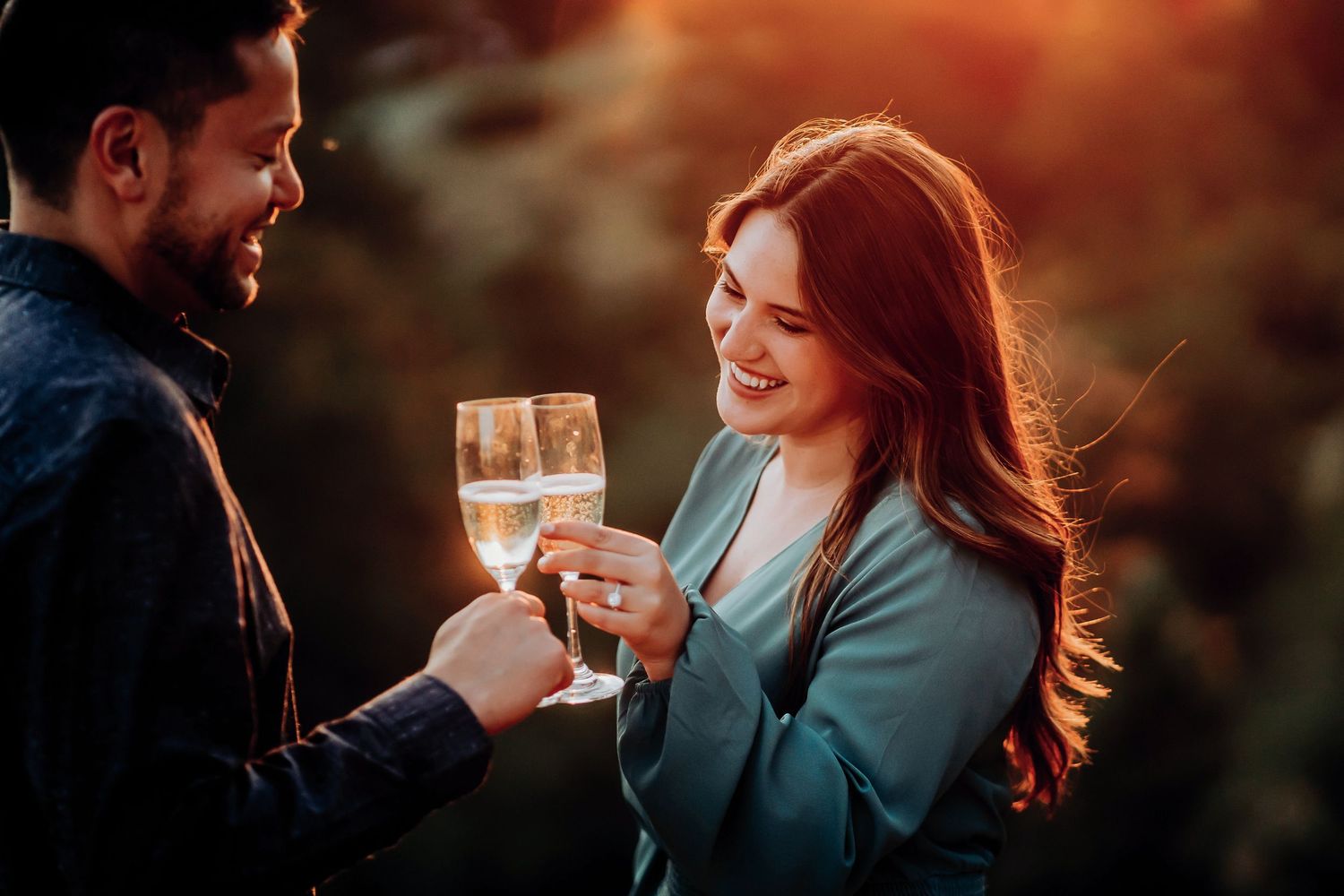 Couple shares intimate moment during outdoor engagement photoshoot with golden lighting.