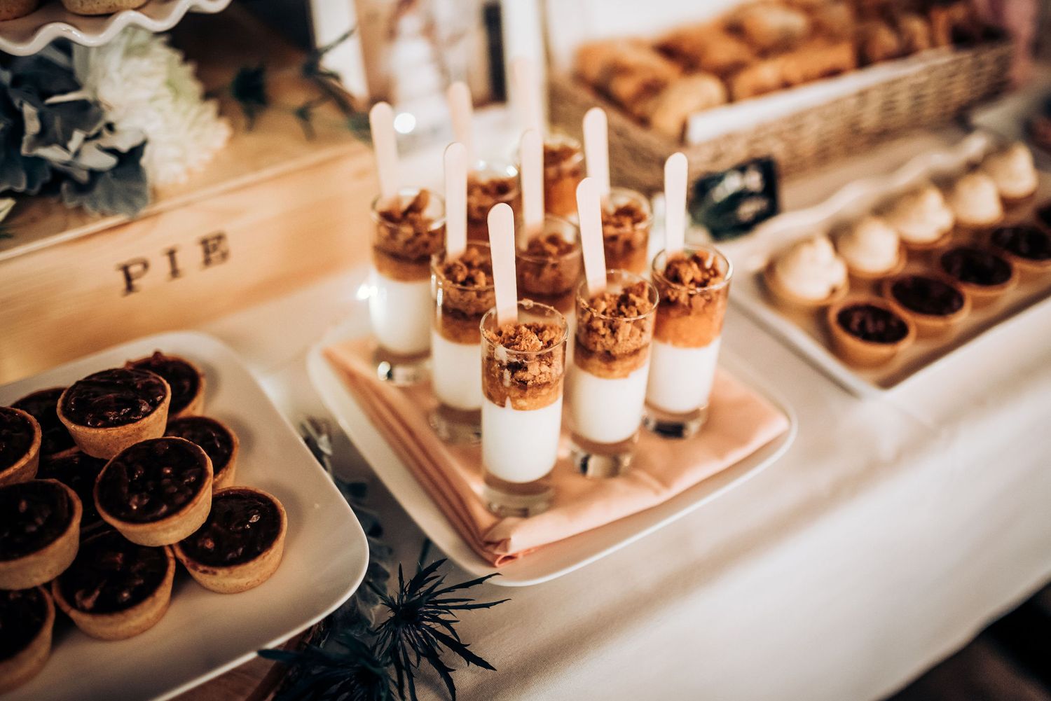 Elegant dessert table with pie slices and layered parfait shots decorated for a special event.