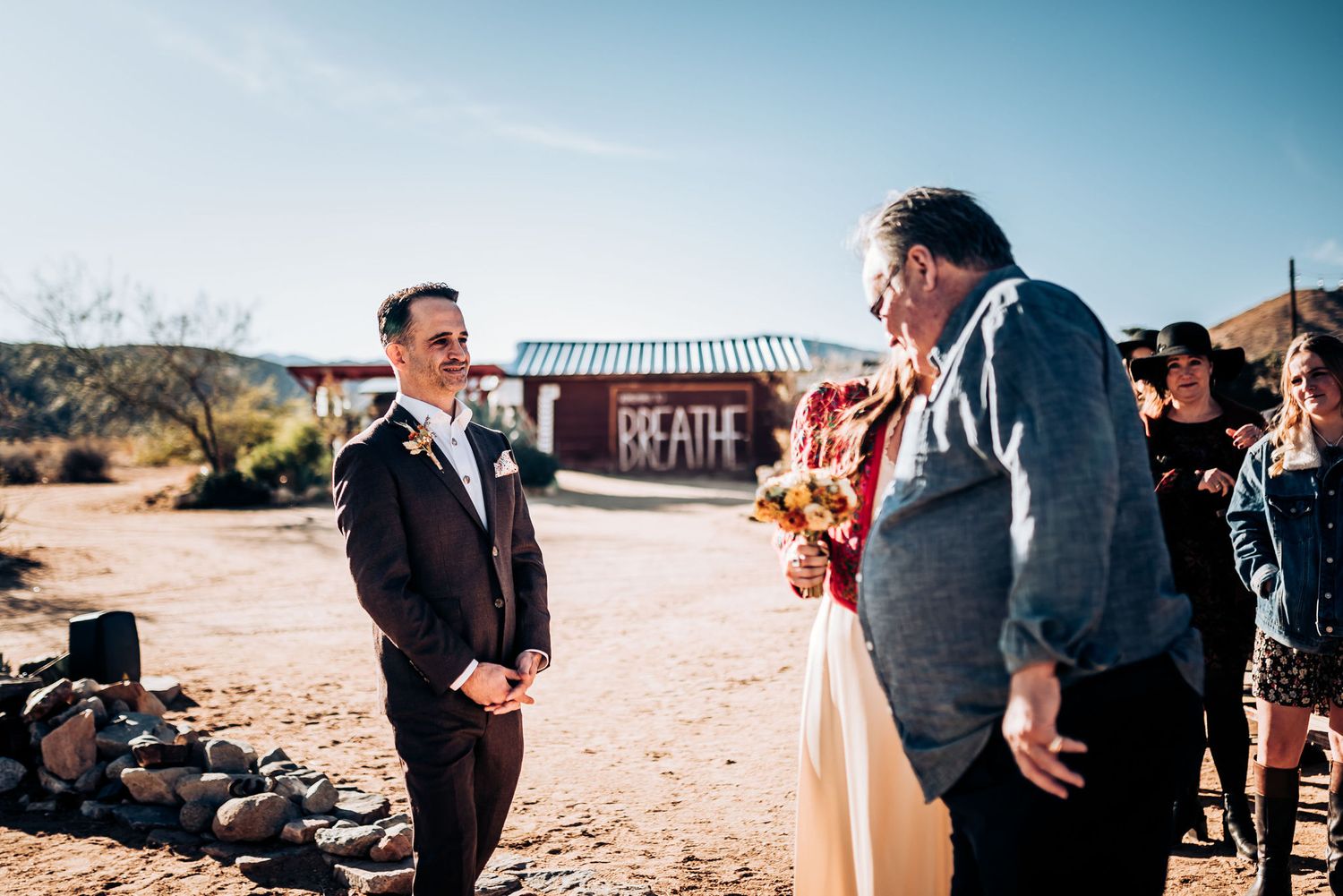 An outdoor ceremony taking place in a rustic desert setting with mountains visible in the distance.