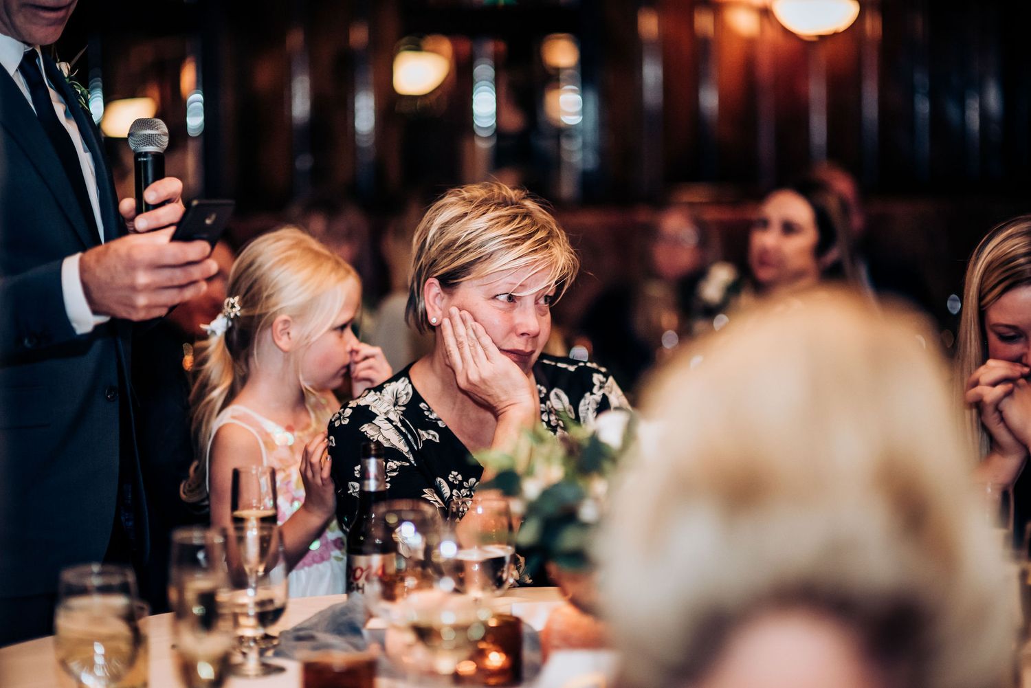 Guests share emotional reactions during dinner at an elegantly set table.