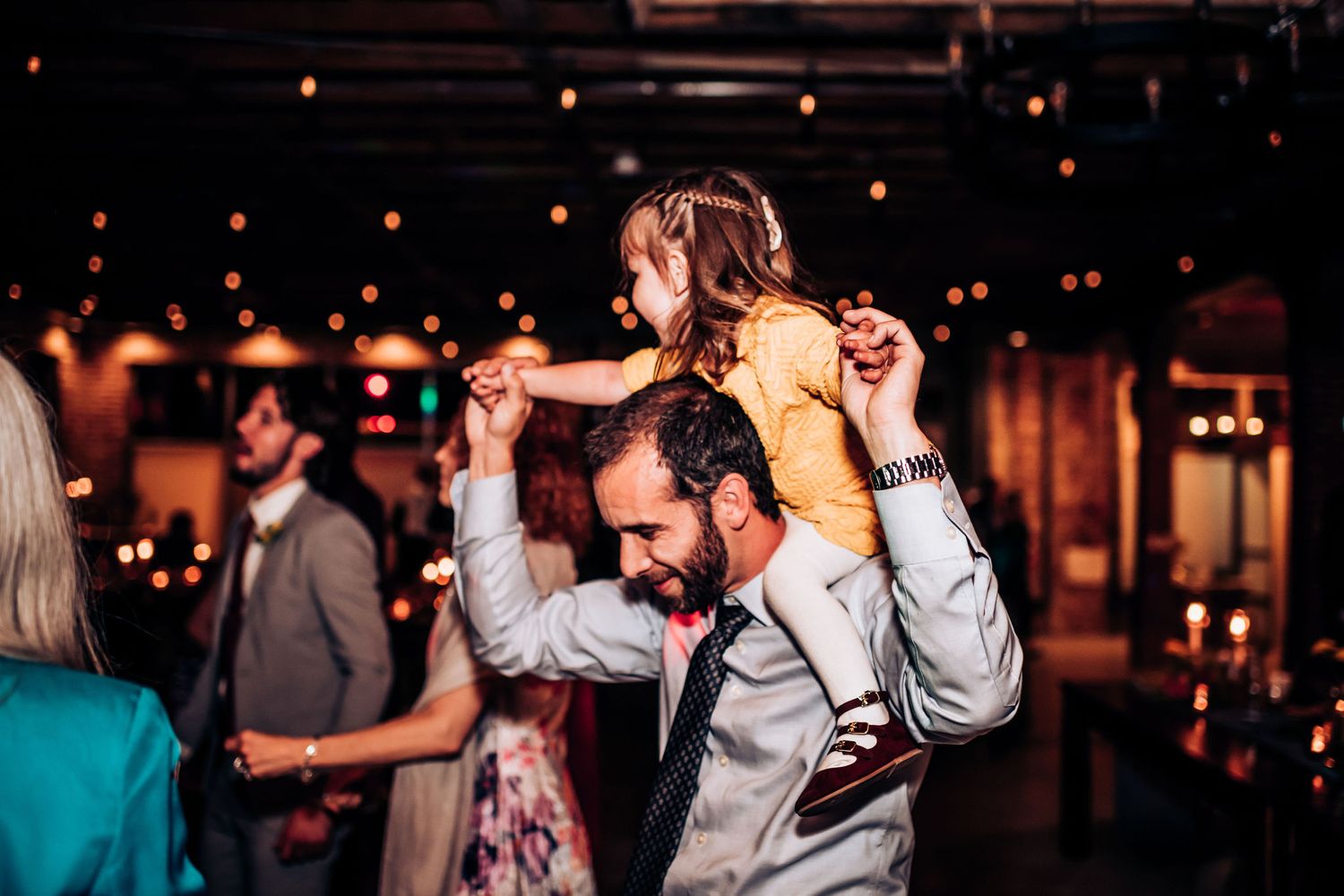 Guests dancing and celebrating at a wedding reception in a dimly lit venue.