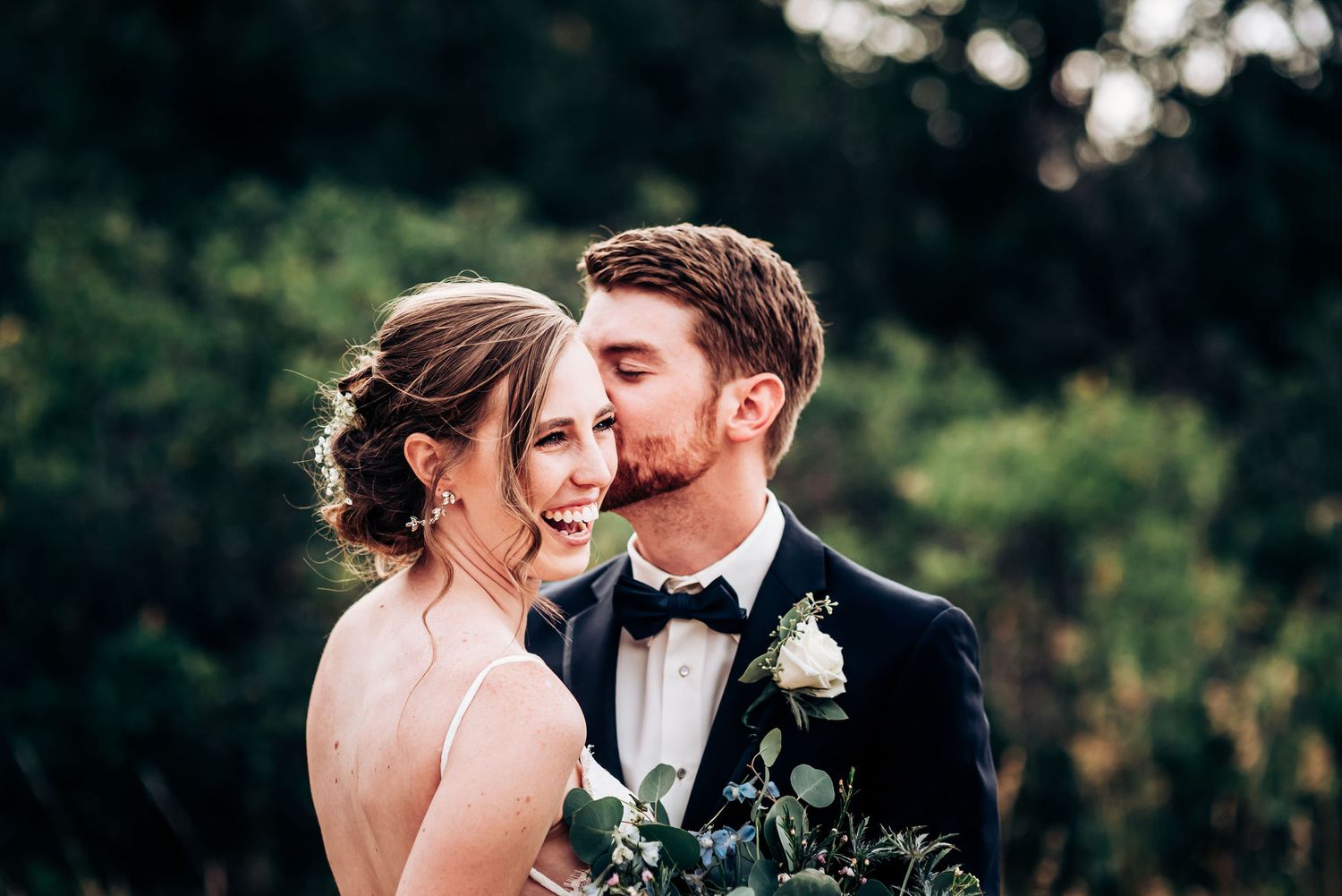 Wedding couple shares an intimate moment in a garden setting with bokeh background.