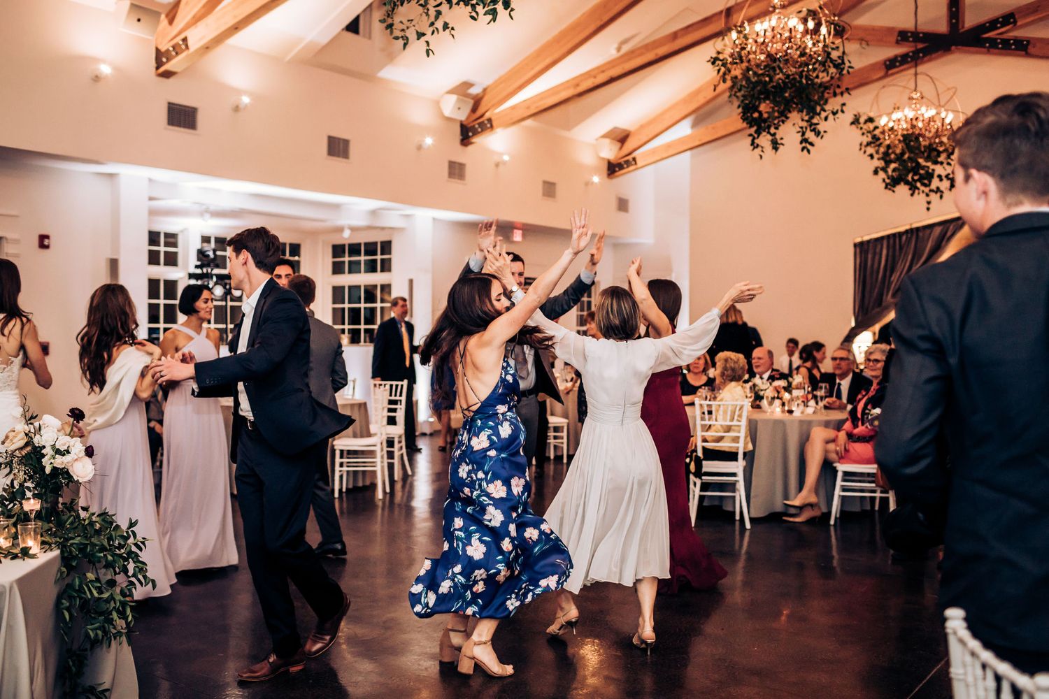 Wedding guests dancing and celebrating on the dance floor under decorative hanging greenery.
