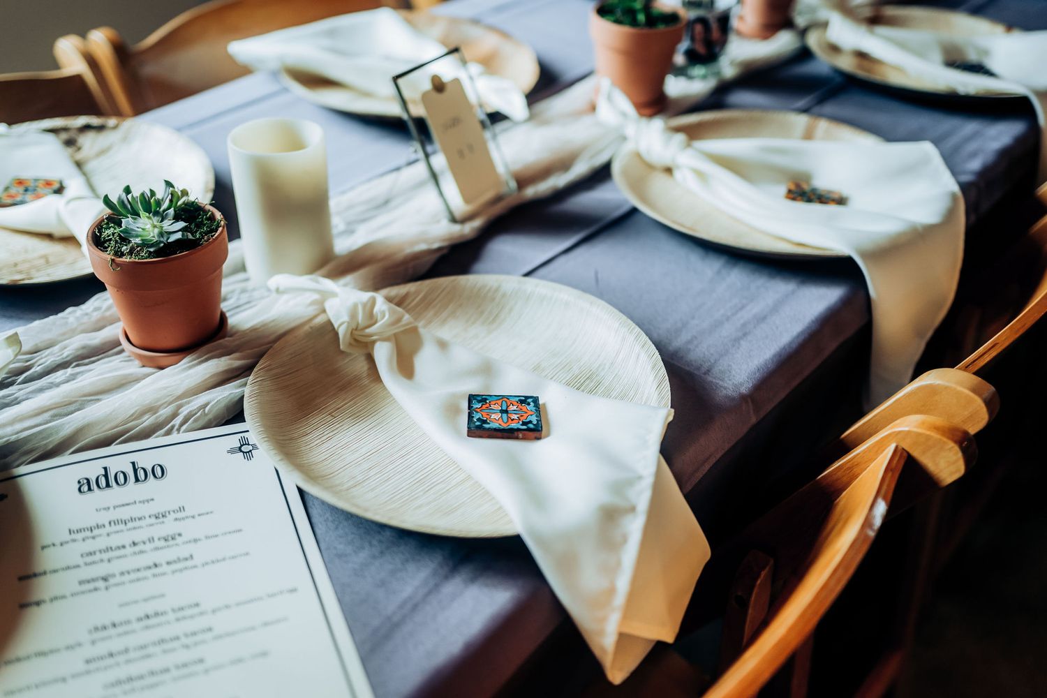 Elegant table setting with menu, plates, and small potted succulents.