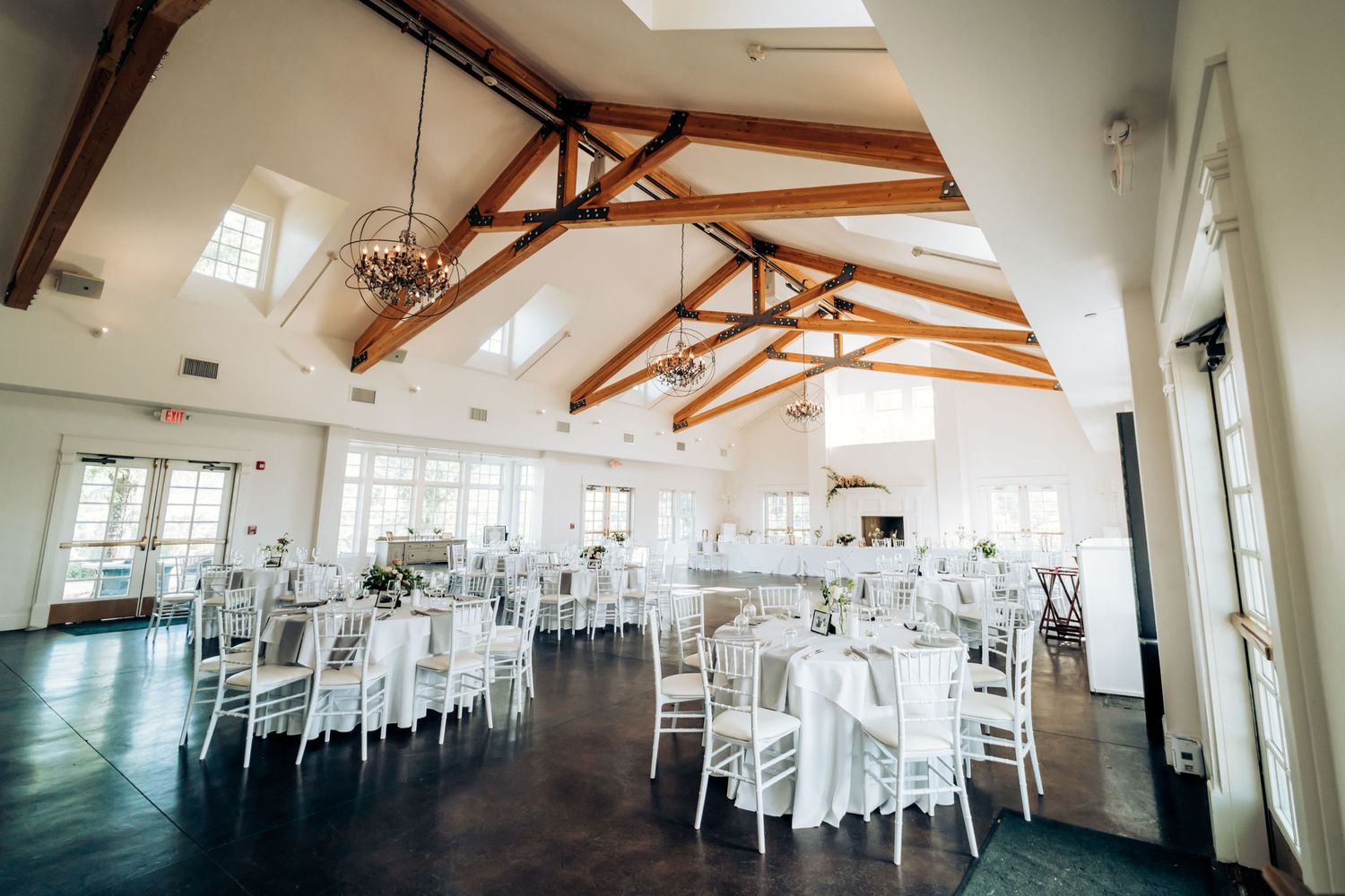 Wedding seating chart displayed on elegant stand with reception hall in background.