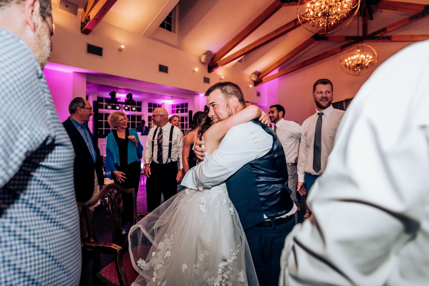 Couples dance together during wedding reception under warm lighting and exposed beams.
