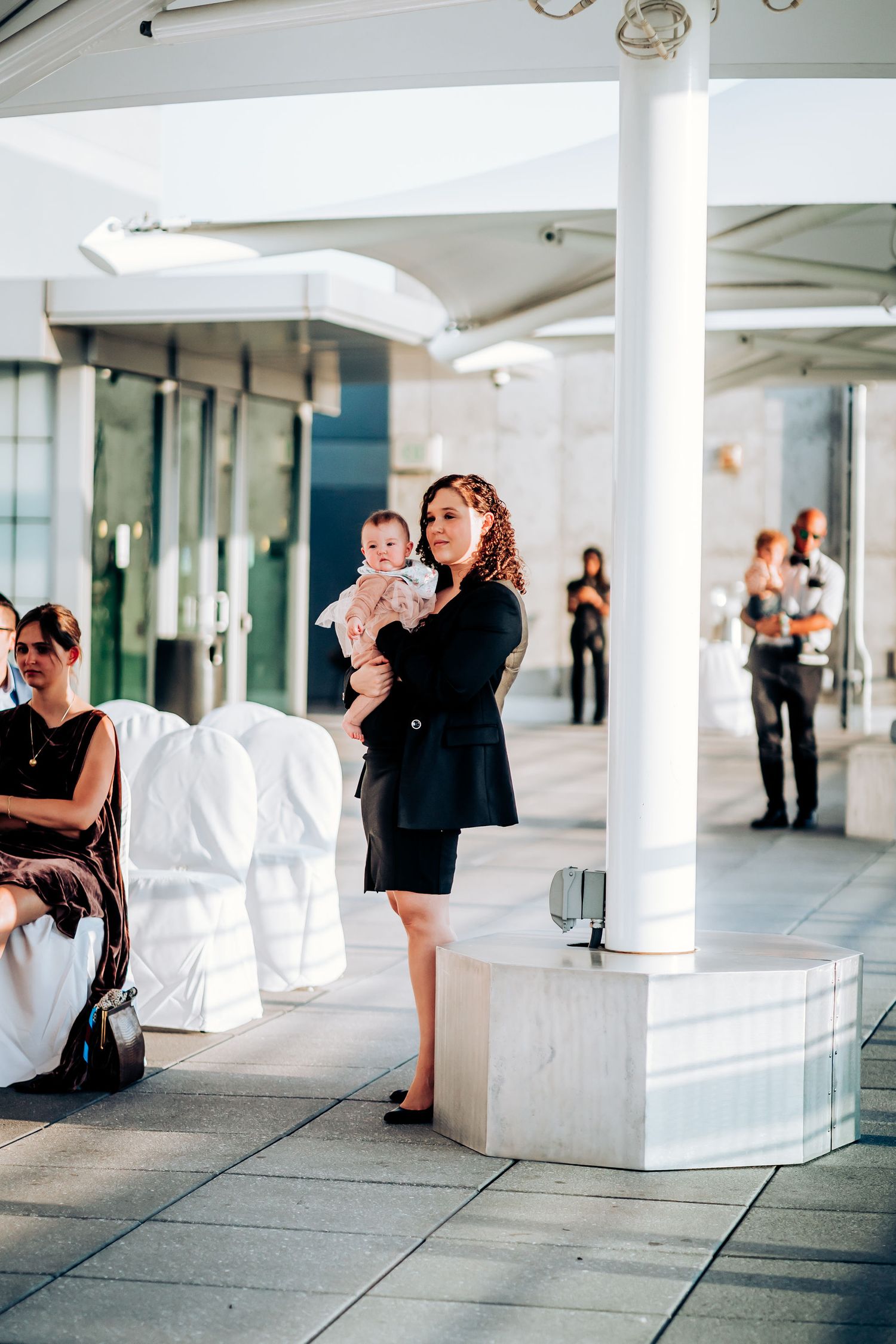 Guest holding baby during modern urban wedding reception.