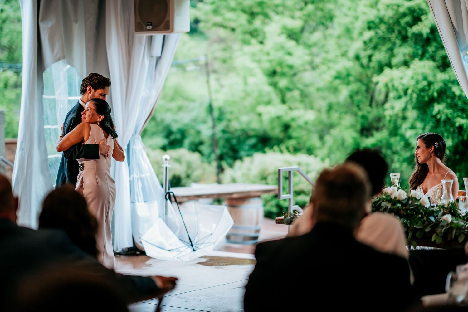 Wedding reception speech being given under draped tent with guests seated.