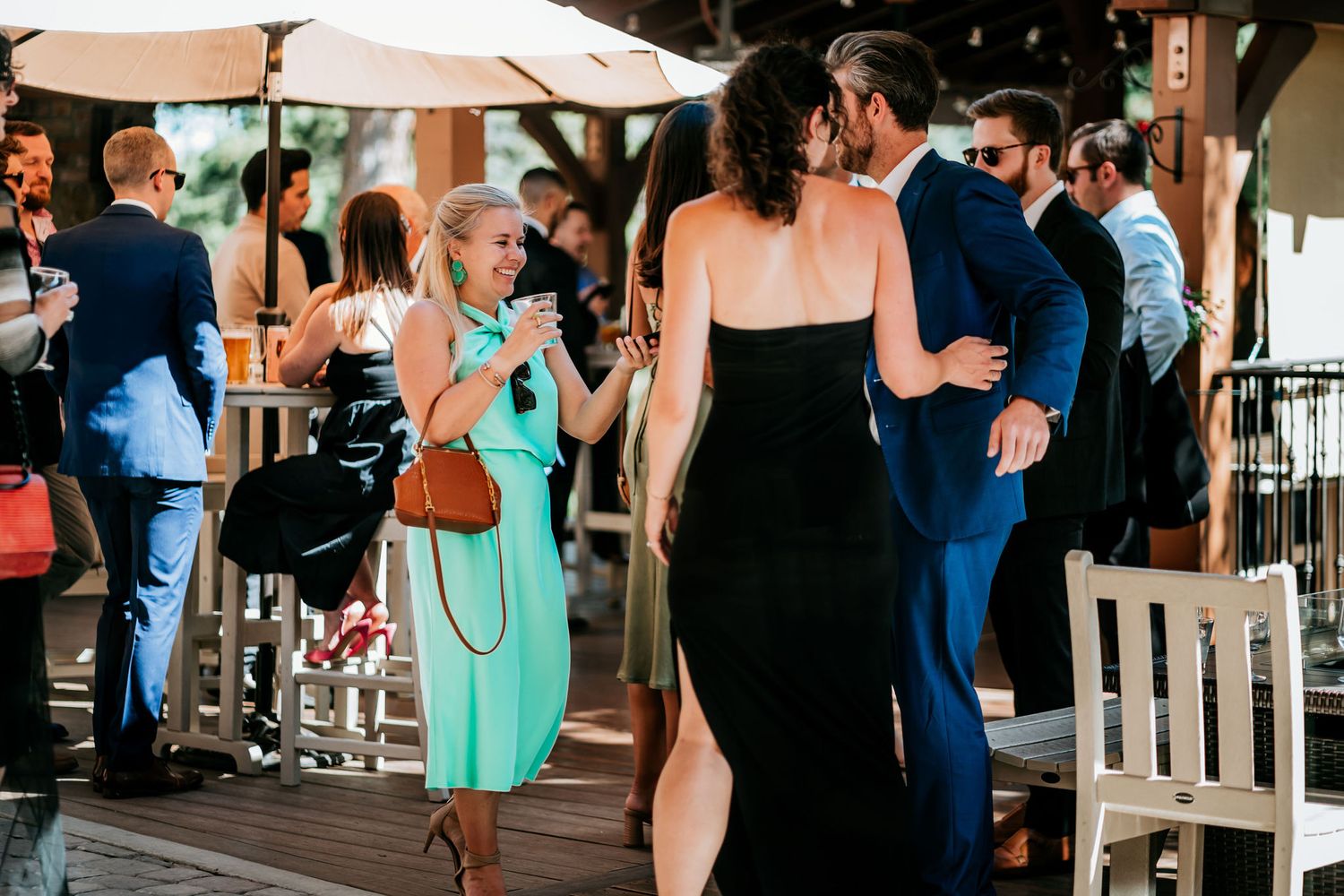 Elegant outdoor reception with guests mingling under patio umbrellas.
