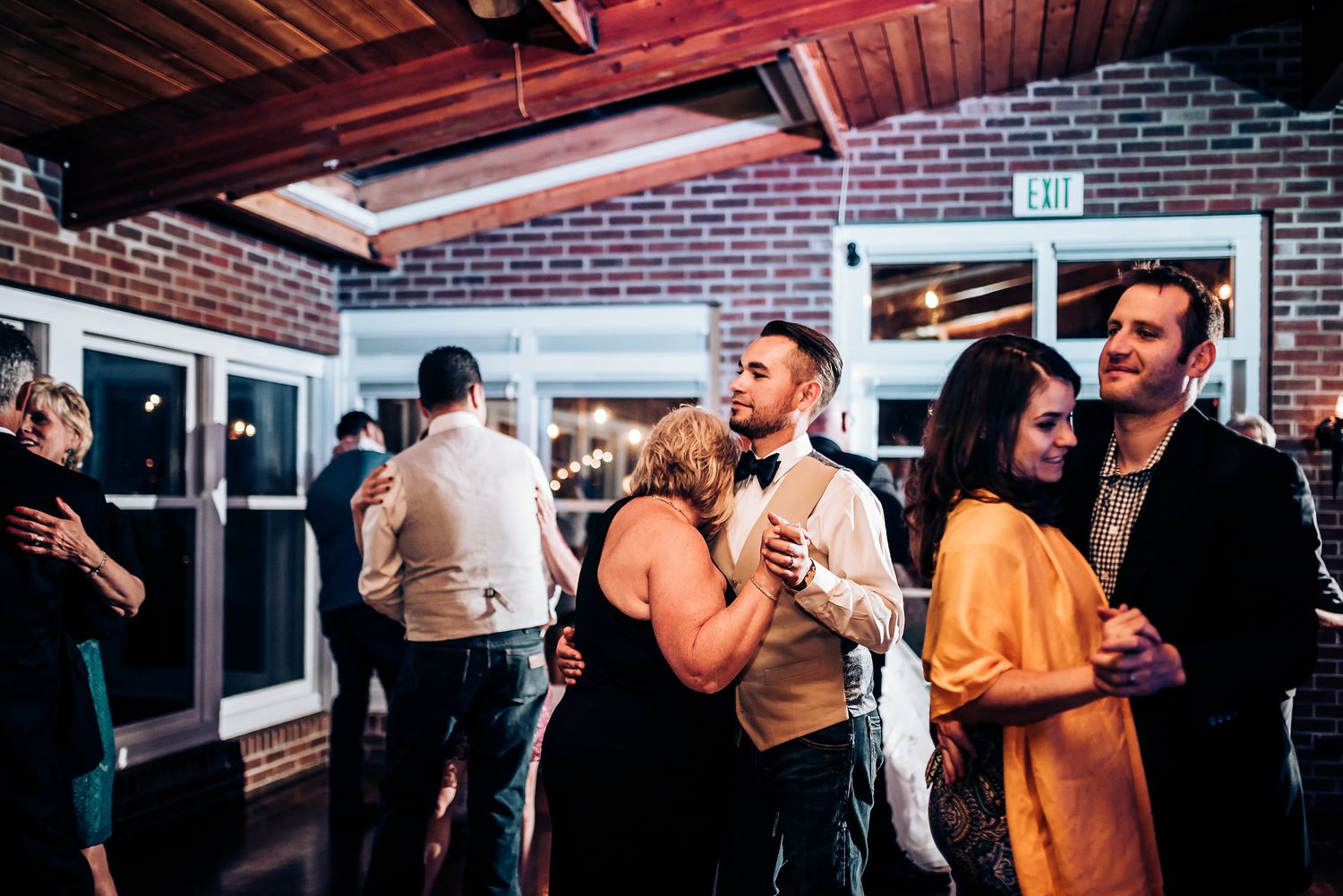 Wedding guests enjoying the reception festivities in a brick-walled venue.