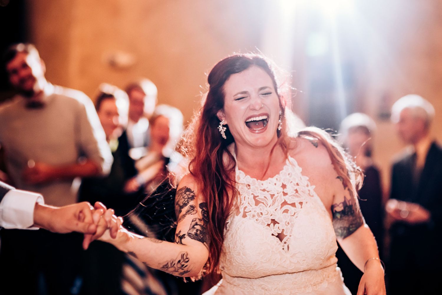 Wedding guest dances joyfully in a white dress at a lively reception celebration.