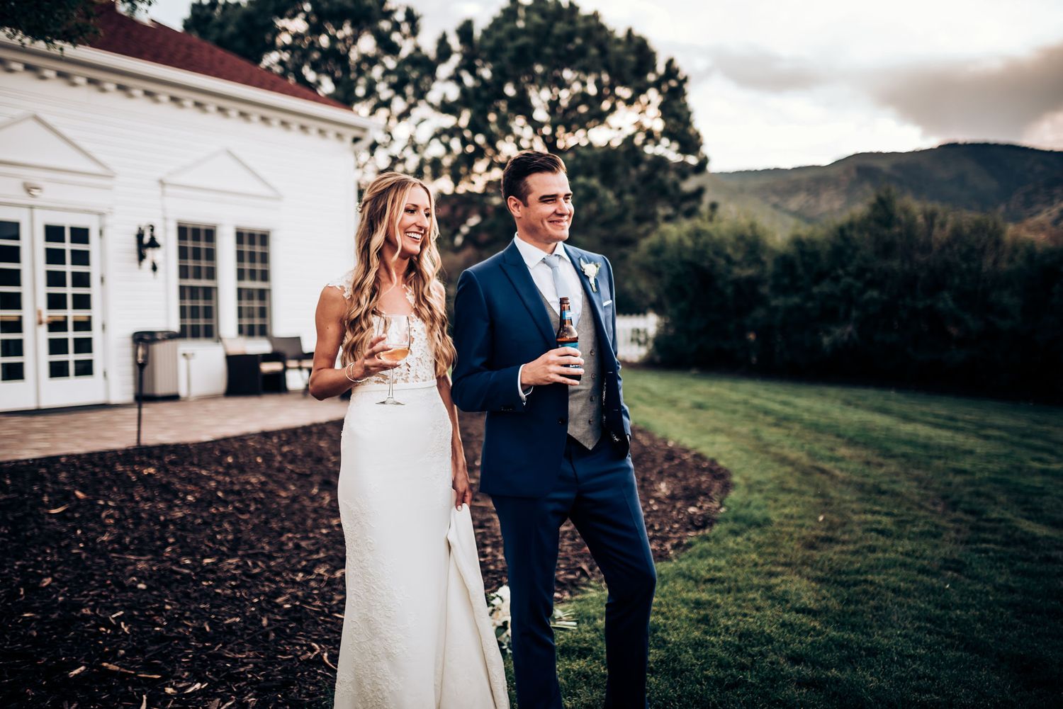 Outdoor wedding portrait at an elegant white venue with mountains in background.
