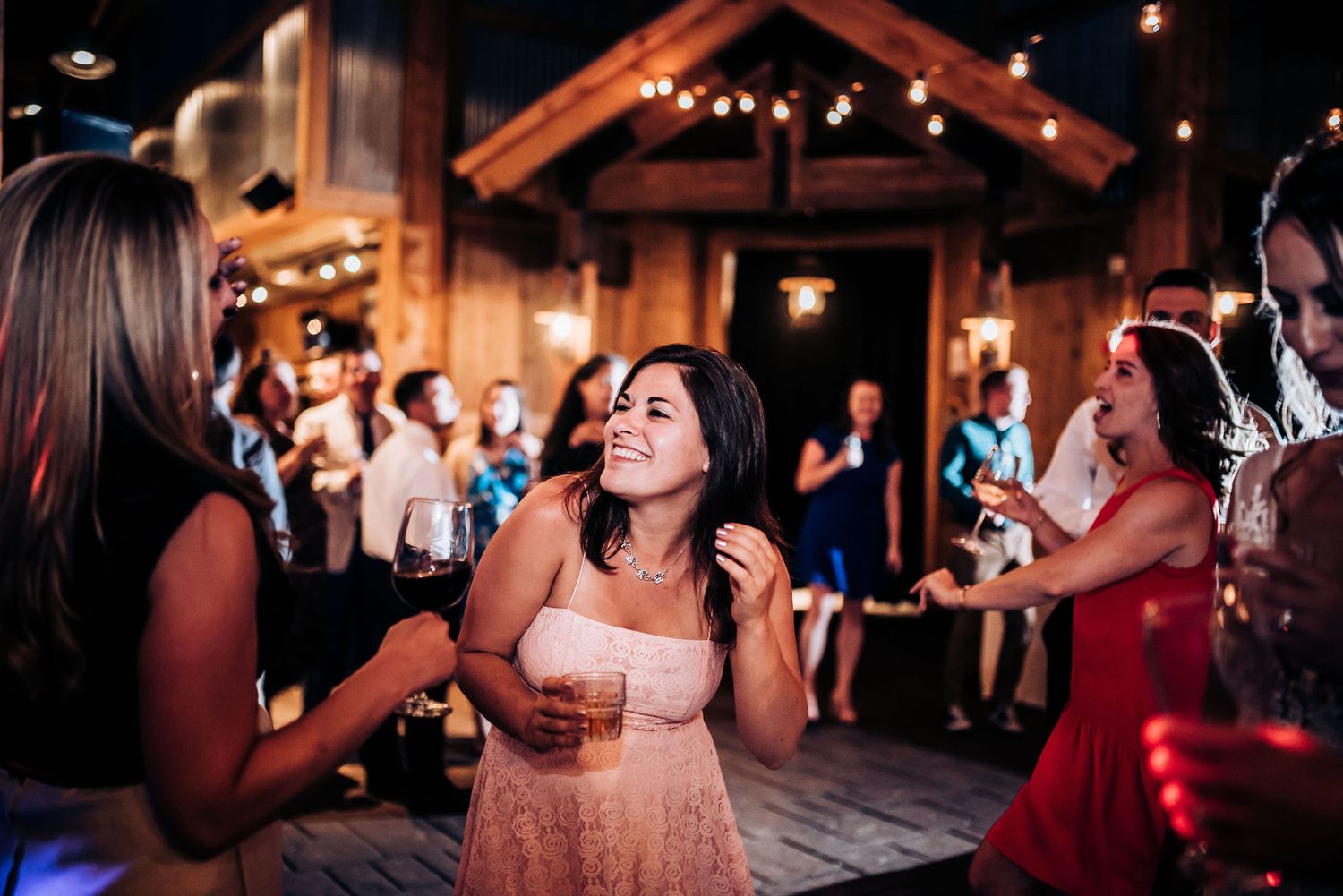 Festive celebration inside rustic lodge with dancing guests.